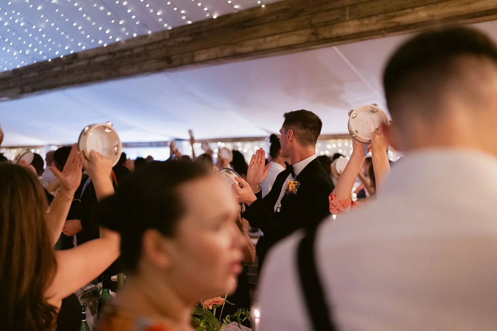guests-shaking-tambourines-couple-entrance-marquee.jpg