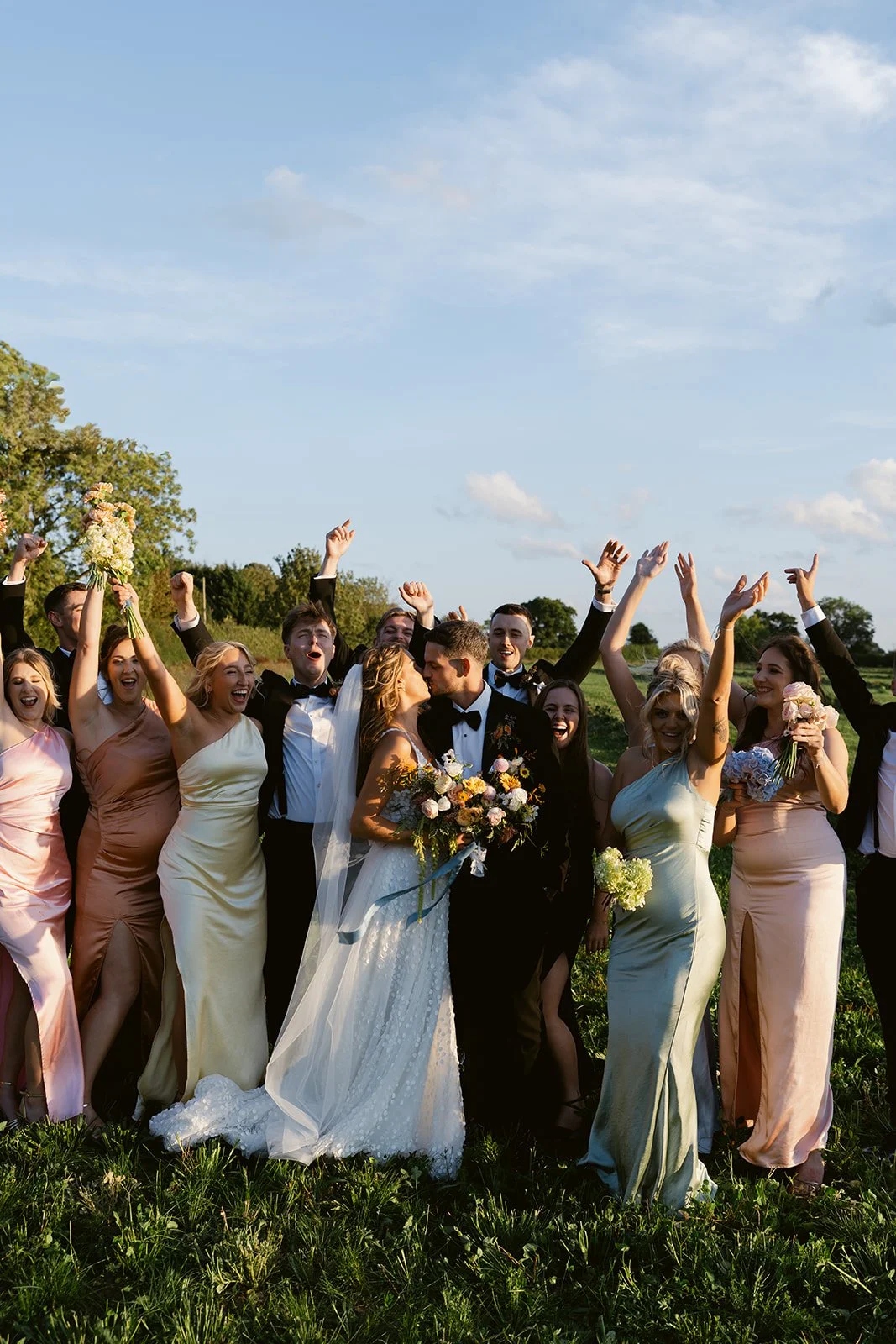 wedding-party-celebrating-golden-hour-couple-kiss.jpg