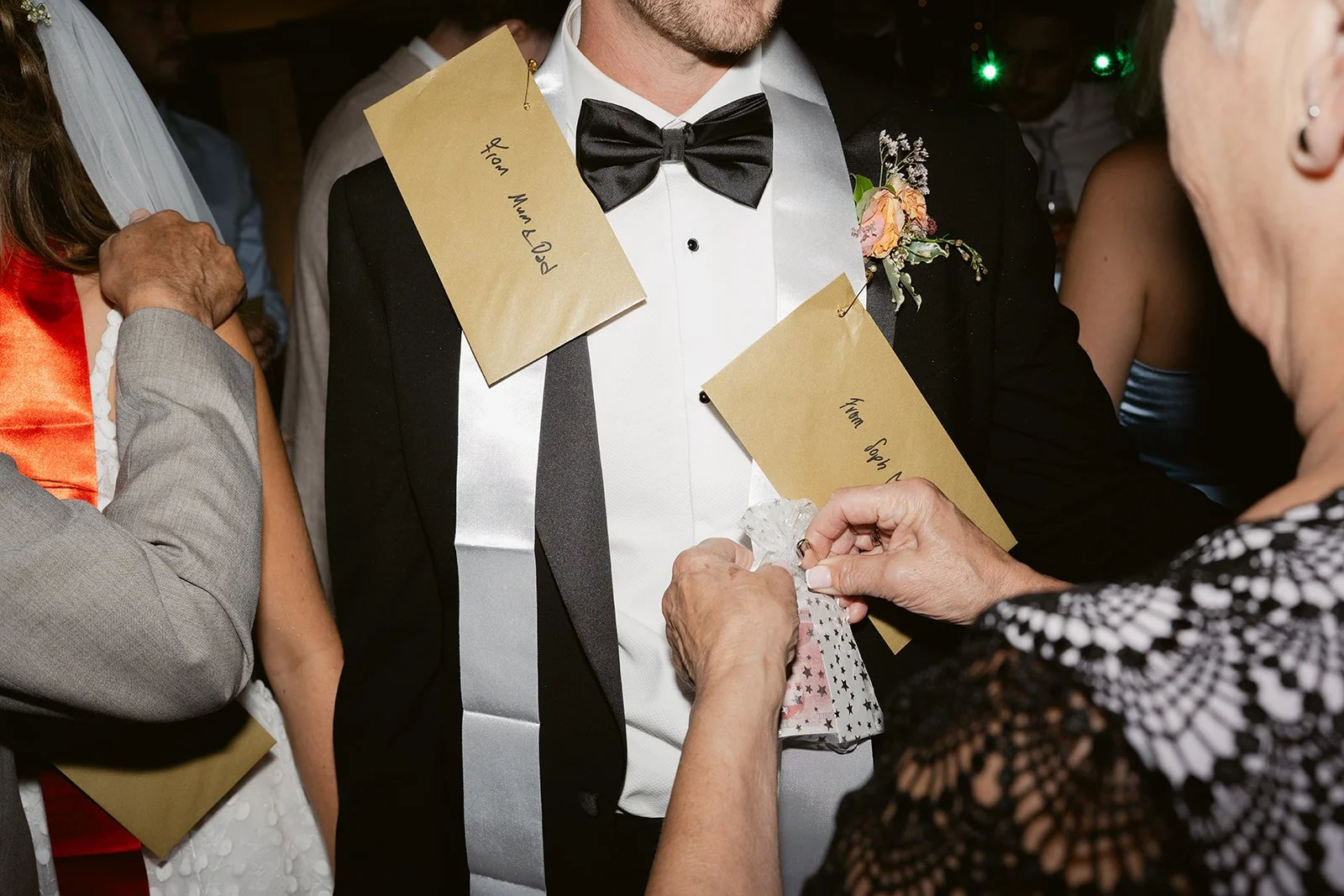 gold-envelopes-pinned-groom-sash-tradition.jpg