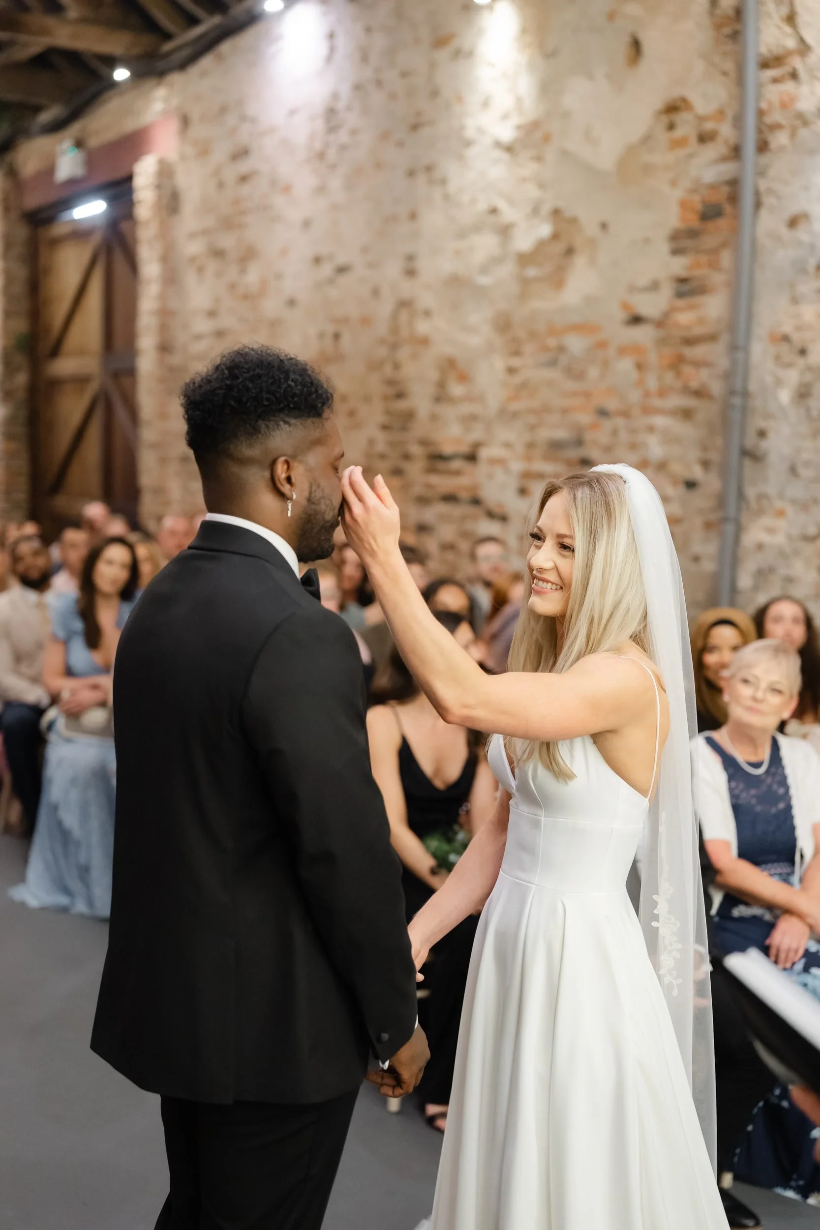 the-normans-bride-touching-groom-face-wedding-ceremony-barn-311.jpg