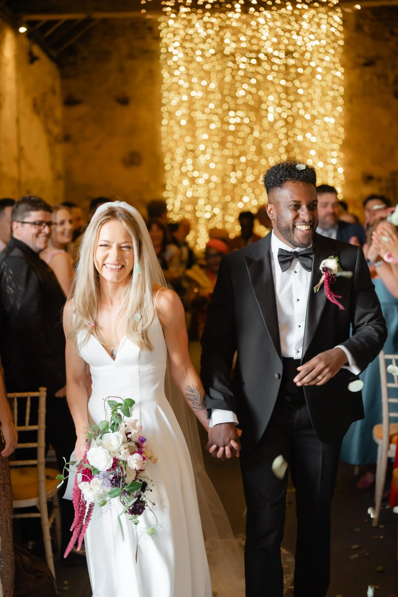 the-normans-newlyweds-holding-hands-aisle-fairy-light-wall-393.jpg
