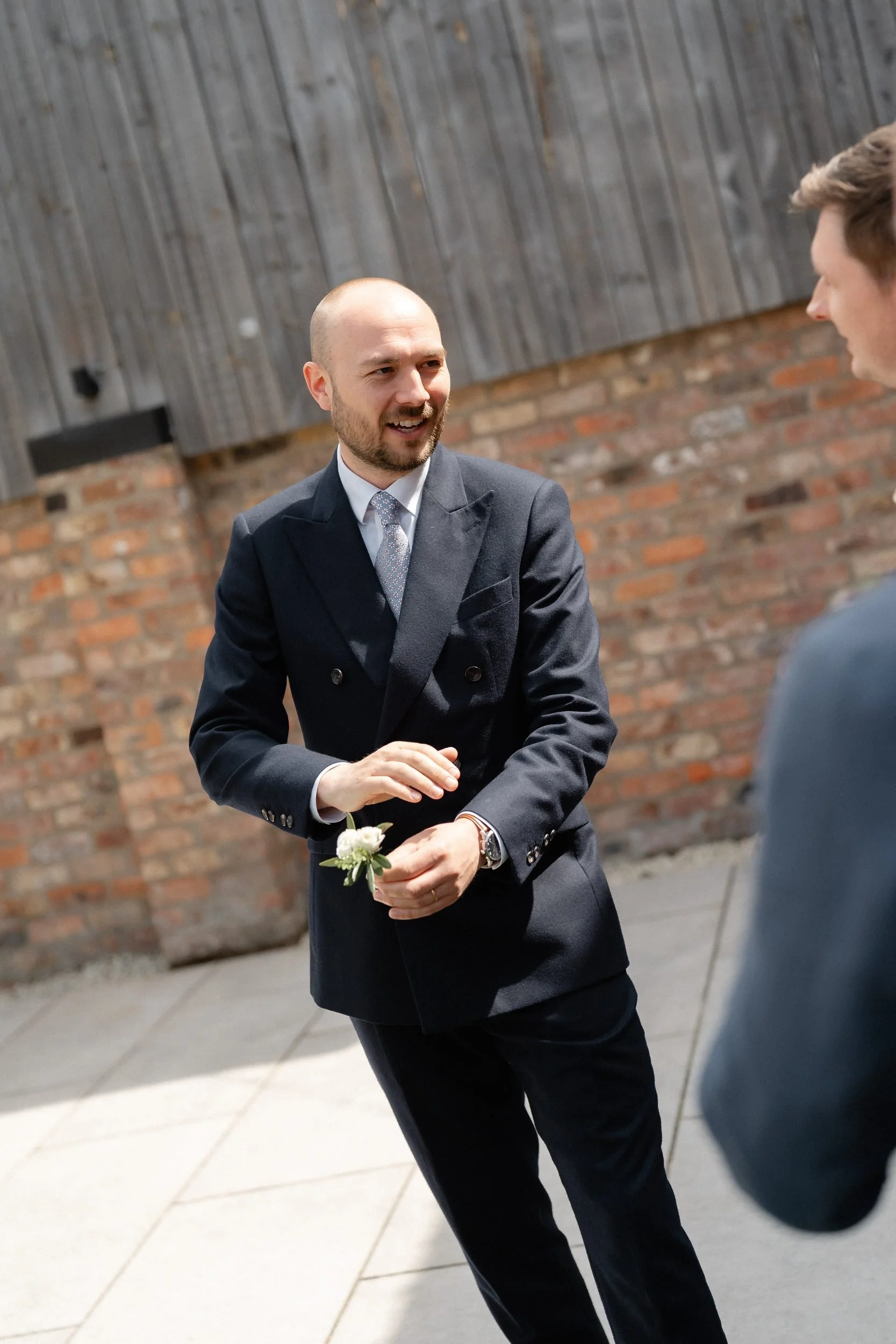 groomsman-fixing-buttonhole-farm-courtyard-64.jpg