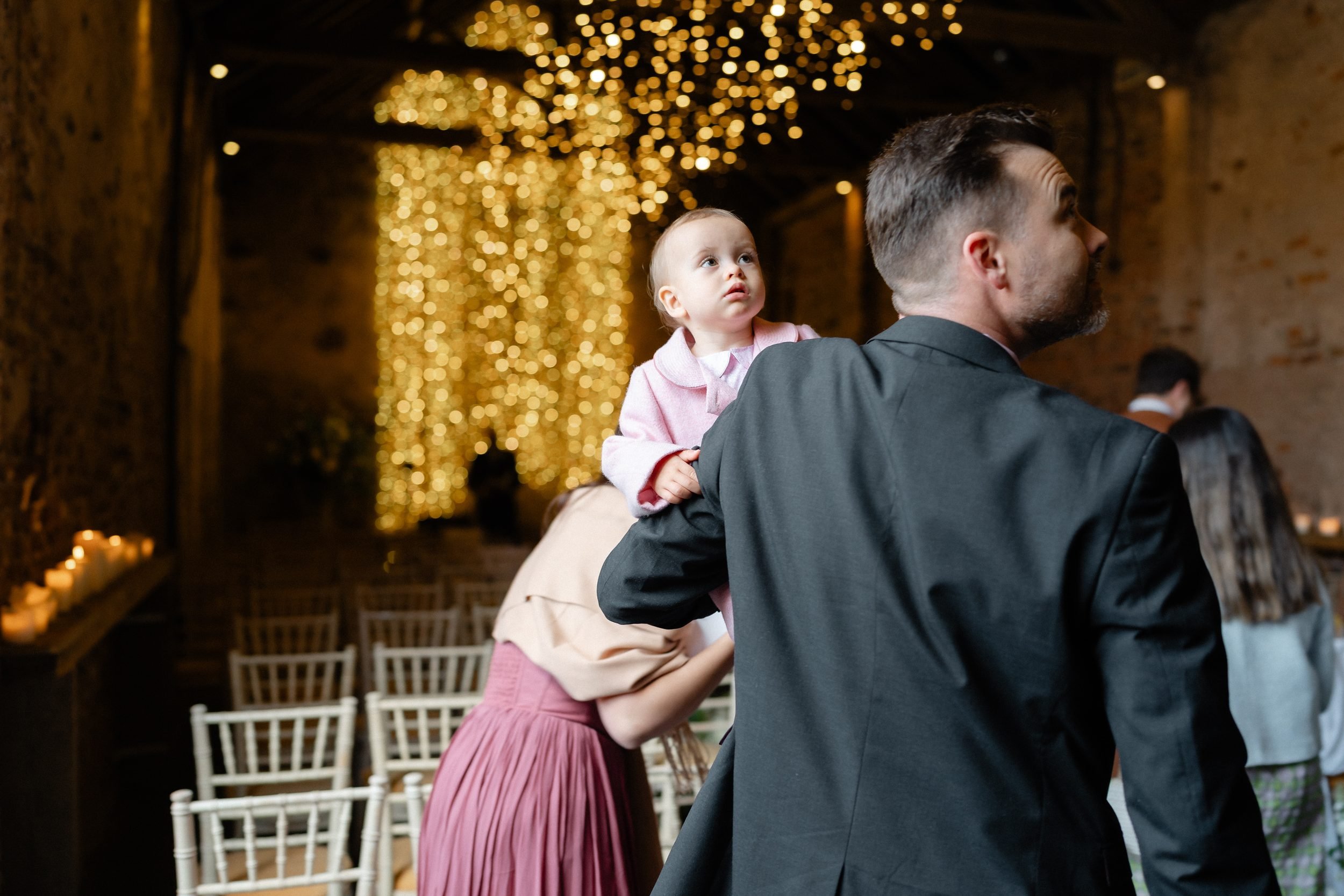 guest-holding-toddler-fairy-light-curtain-ceremony-barn-202.jpg