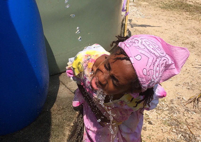 A local girl drinks fresh water straight from the source.jpg