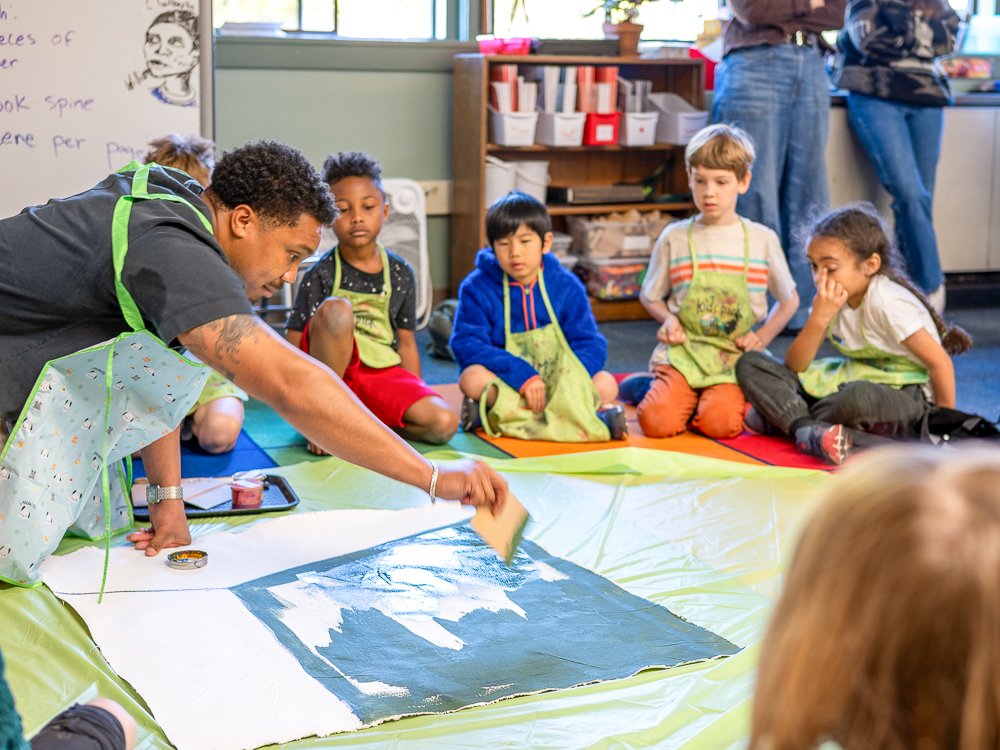 teacher demonstrates painting to students
