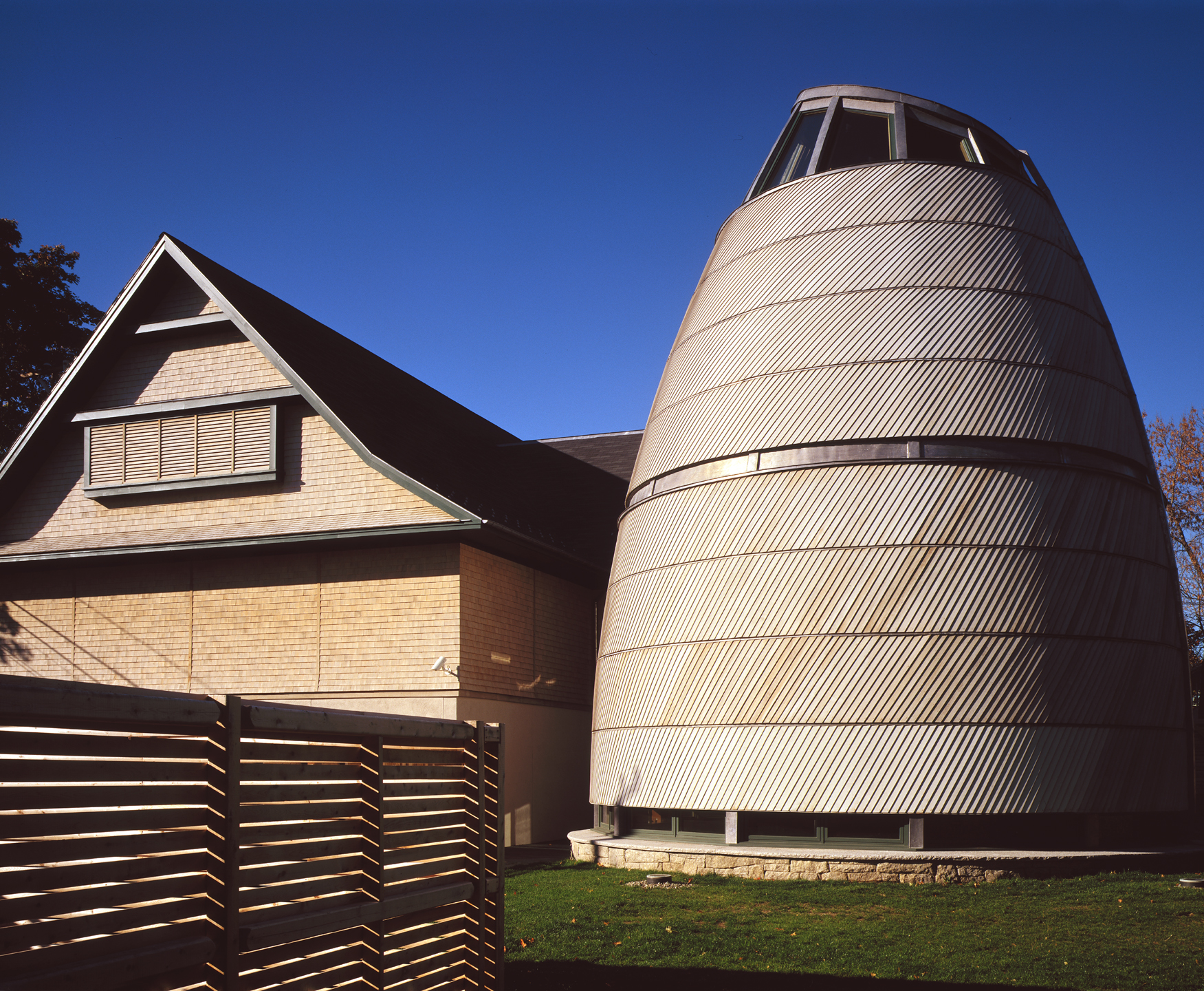 The new gallery (left) compliments the existing building, while the new Circle of Four Directions integrates Wabanaki forms and patterns with a shingle-style material palette