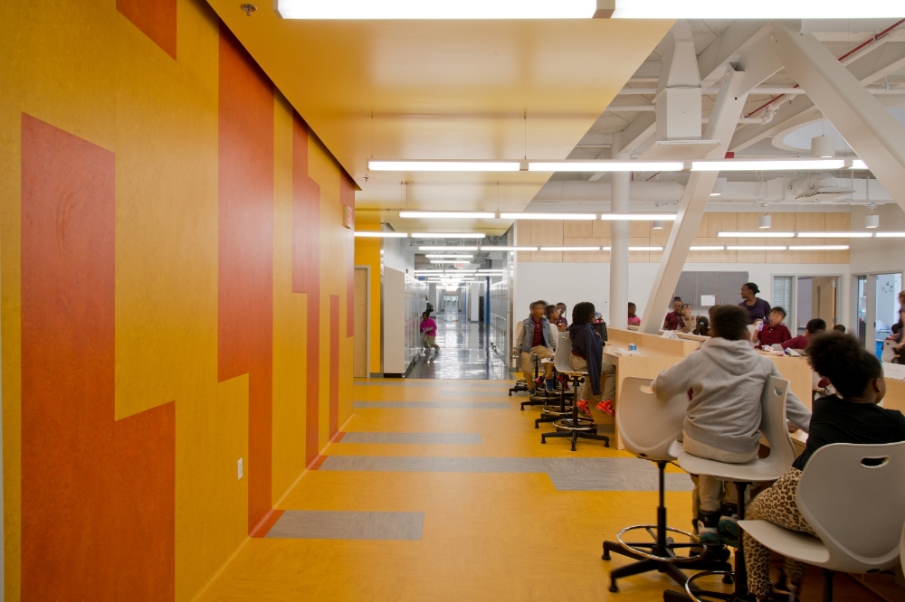 Environmentally-friendly and naturally anti-bacterial linoleum is deployed on both floors and walls to bring color to the commons area in each classroom cluster.