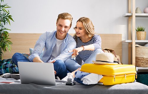 Couple surrounded by vacation items looking at a laptop searching for the perfect Seaside Park vacation rental