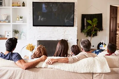 Family sitting on couch in coastal designed living room watching TV in a Seaside Park vacation rental