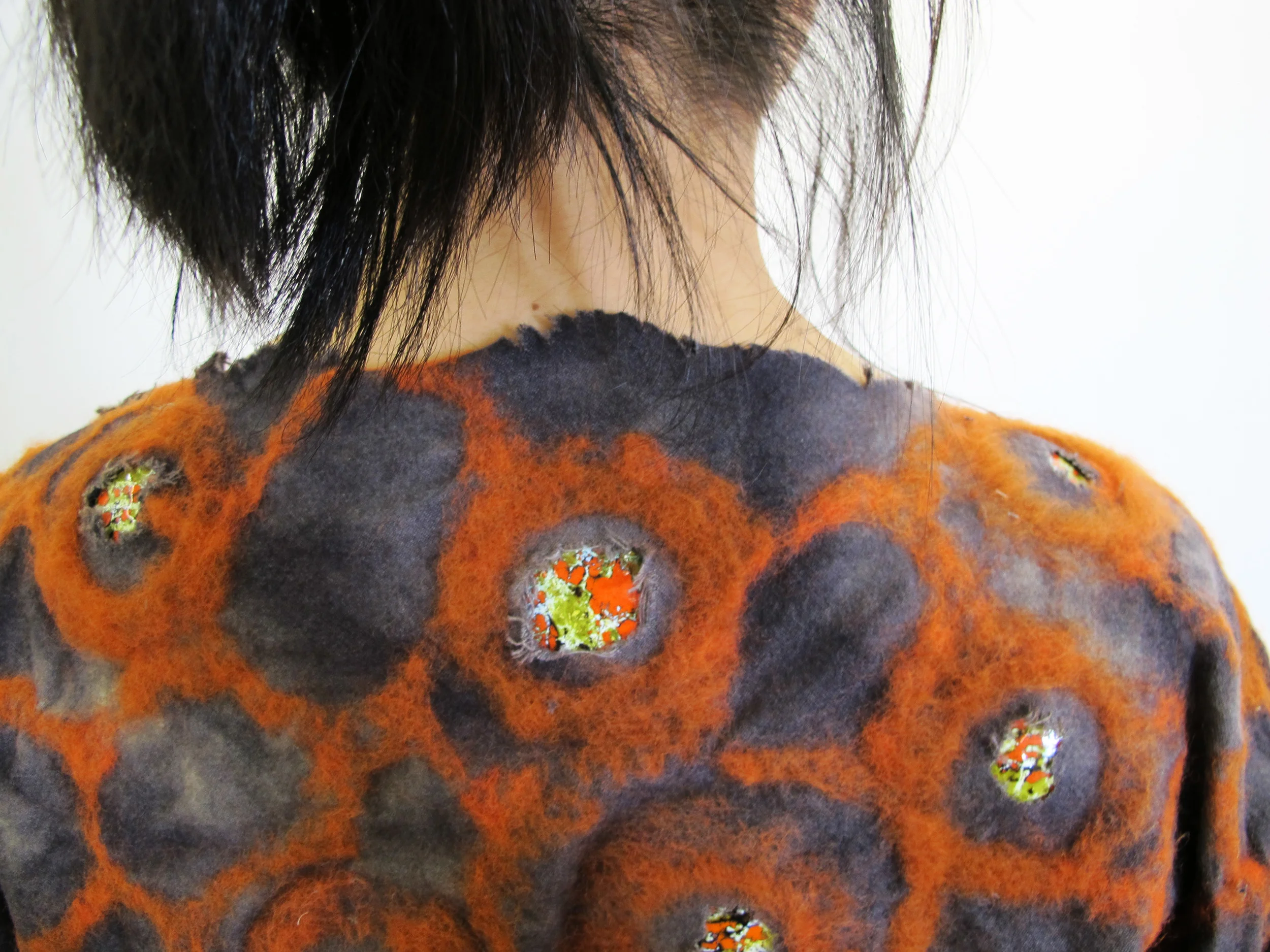 Dyed wool garment with needle-felted wool and enamel pieces.