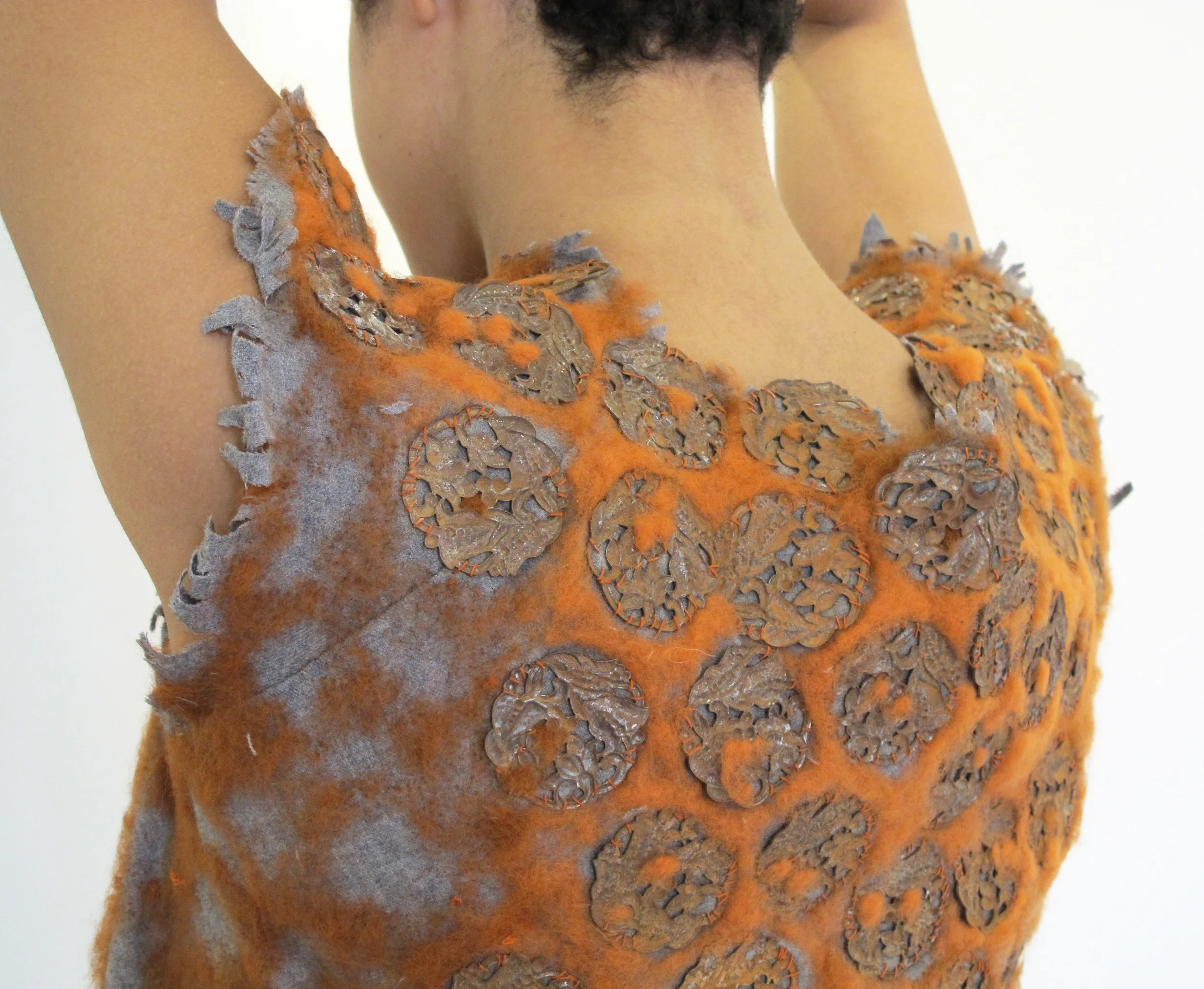 Wool garment with needle-felted wool and rusted metal pieces.