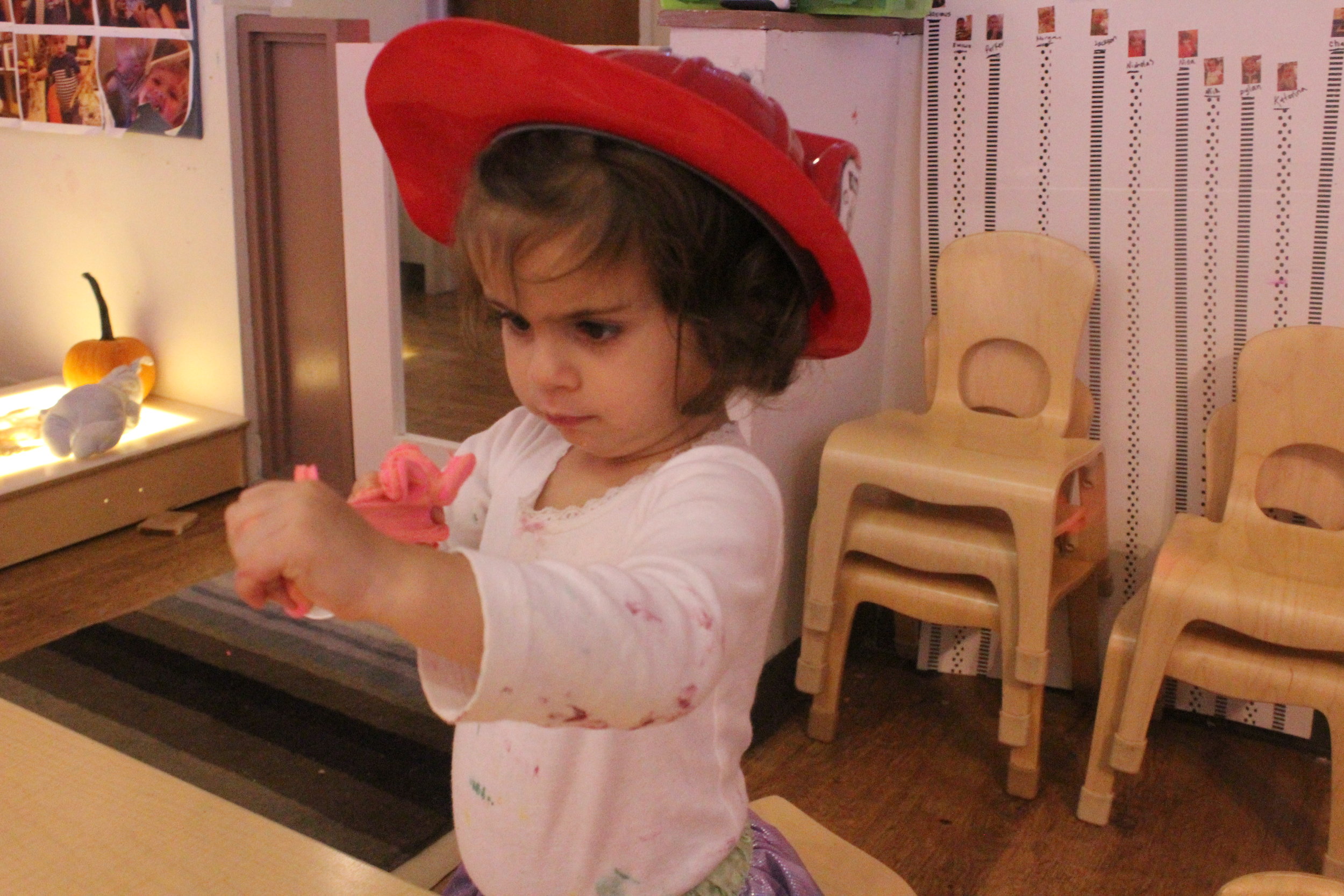  Lately, Nina has really enjoyed exploring dramatic play and all of the sartorial items that go along with it!&nbsp;In this photo Nina is putting a "fire out!". 