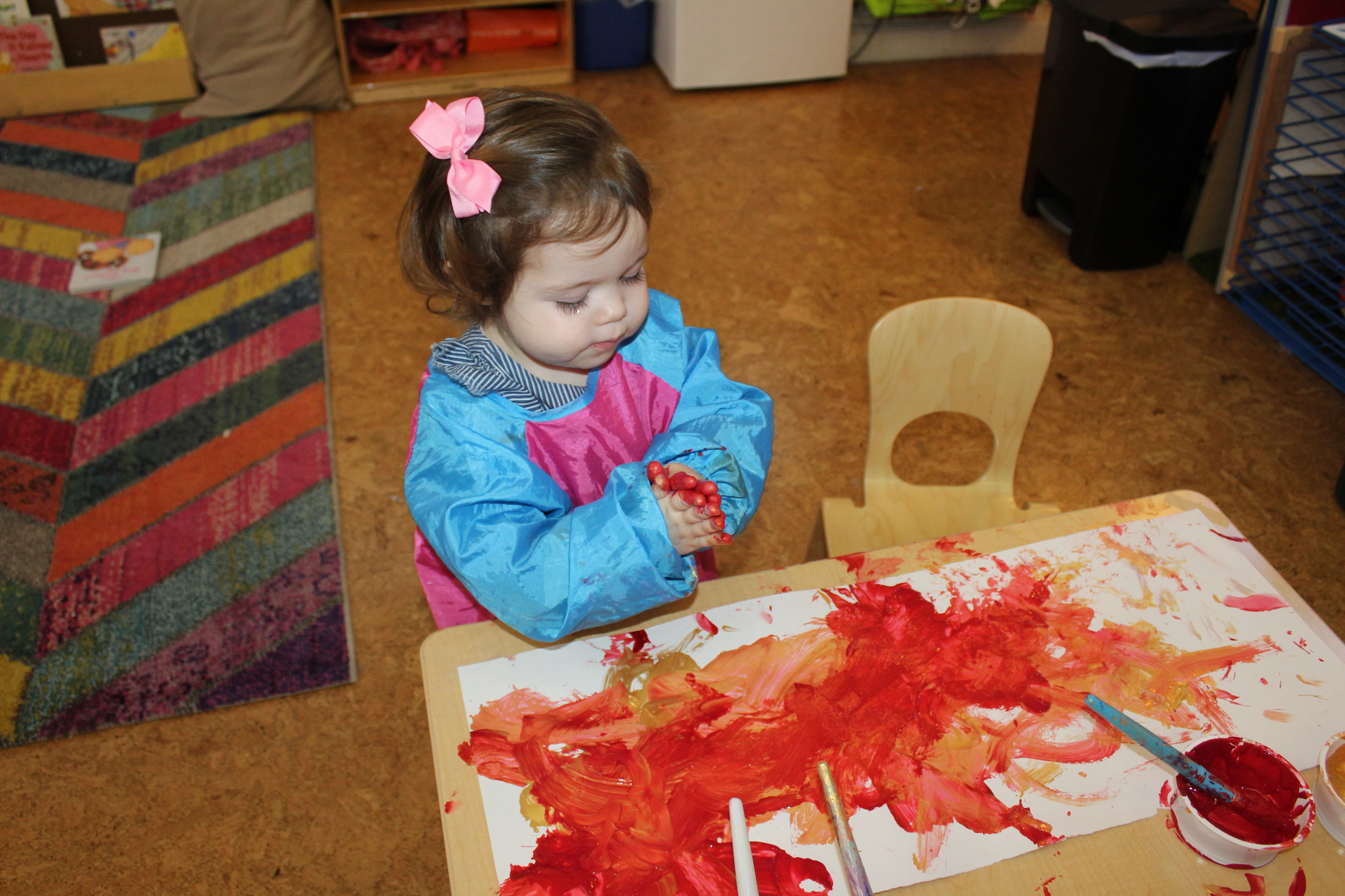  Edie looks at the paint and paintbrush but decides to explore with her hands.&nbsp; As she explores with her hands, she is simultaneously exploring color and texture.&nbsp;Art opens up new worlds for young children and gives them a variety of experi