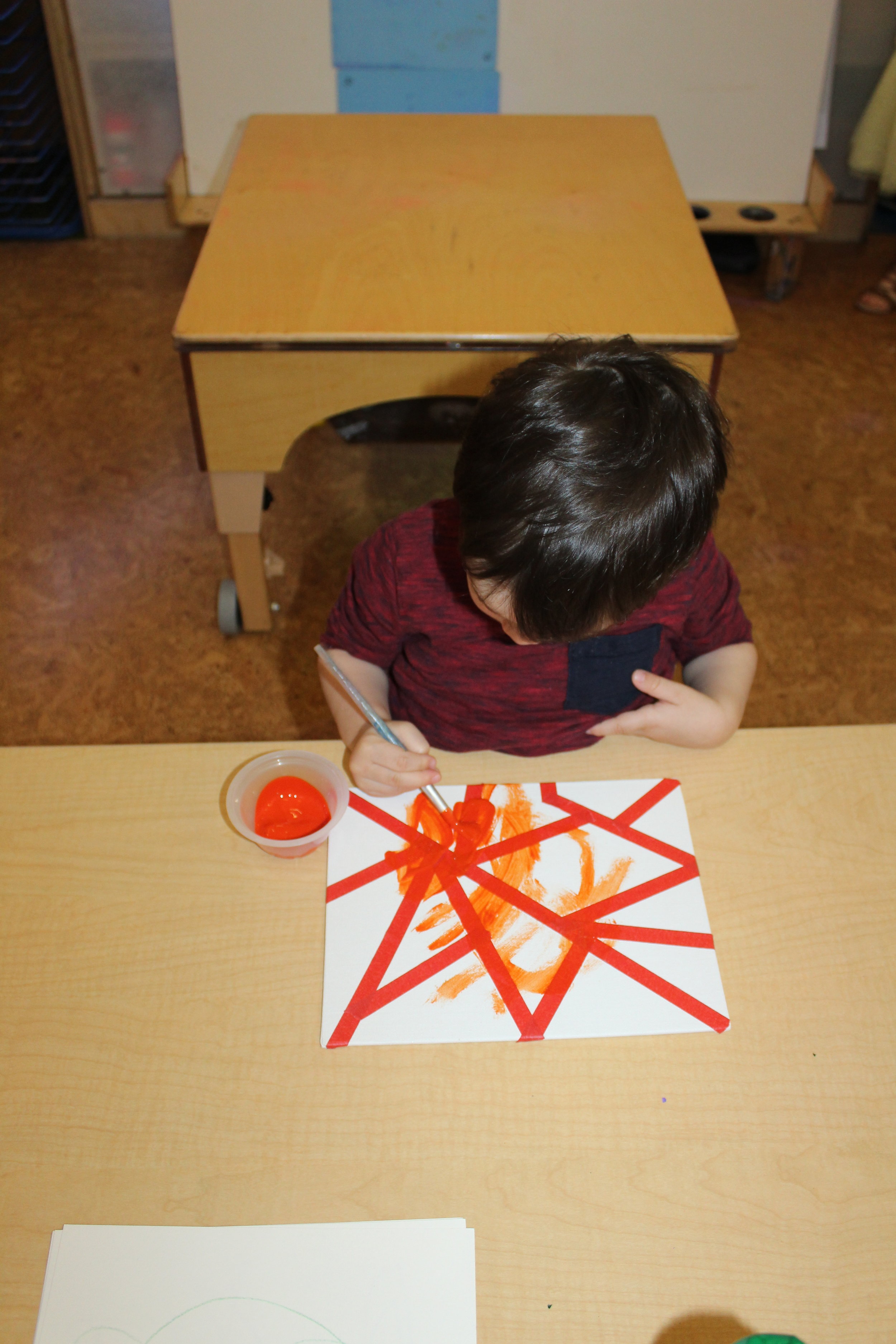  Using green, yellow, and orange hues, tape, and a rectangle shape canvas will make an art piece&nbsp;intriguing. The children appeared interested and amazed, as they observed the abstract design that was created by using different tools and material