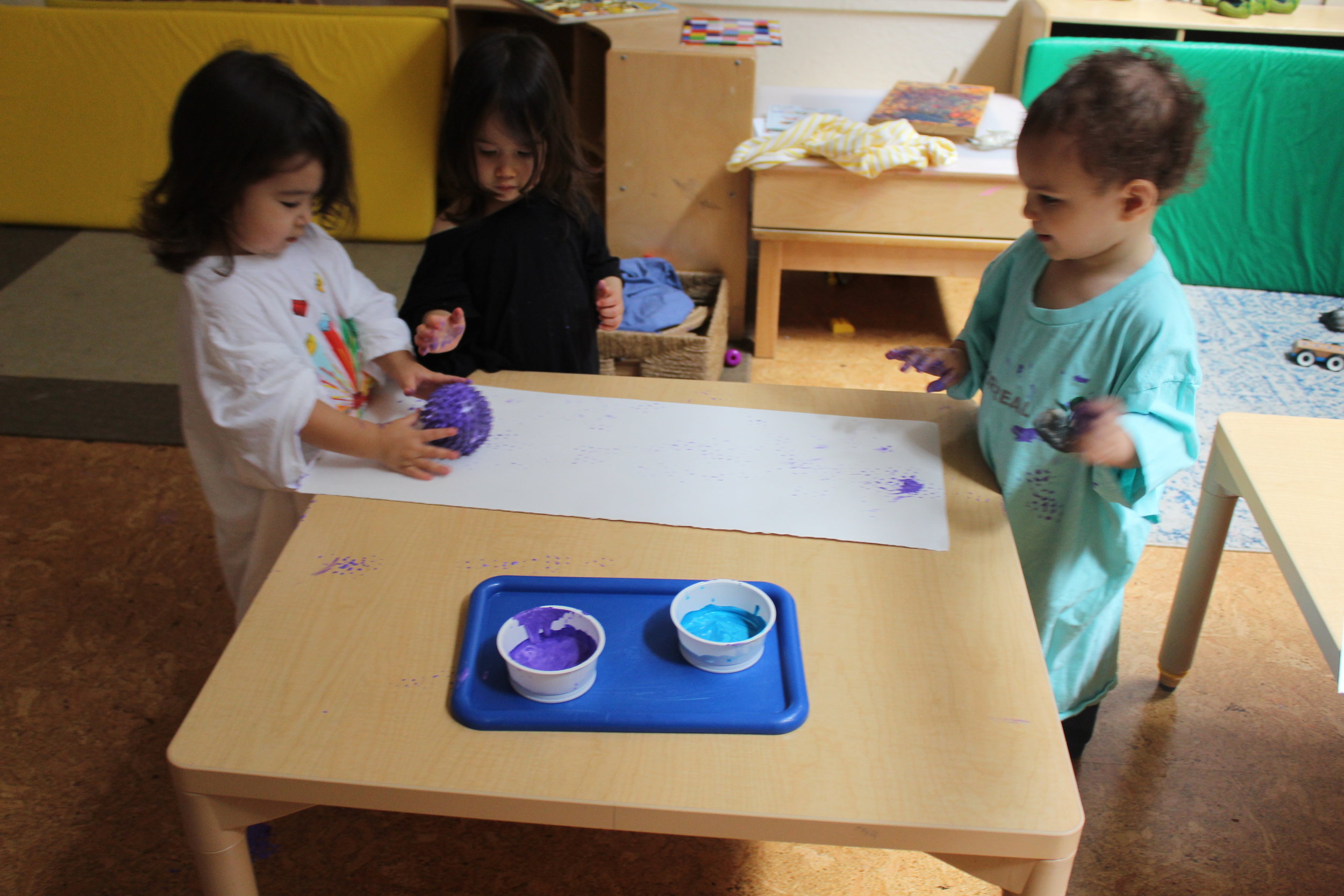  Painting with balls creates a different kind of texture on paper, as the children roll the ball back and forth. They are learning about color, texture, and creating art. 