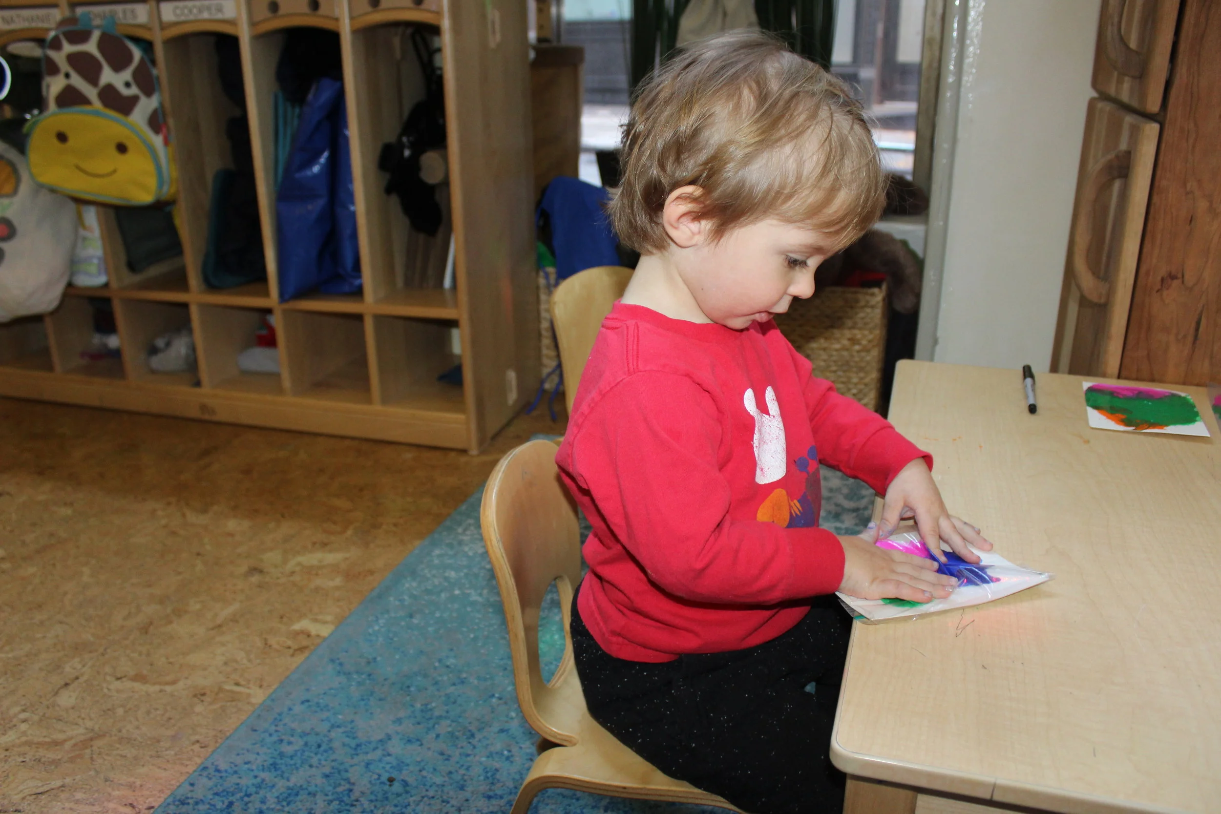   Ziploc Painting:   Charles spreads the paint with his hands and fingers, allowing the colors to move in different directions. He looked curious as he pressed, patted and noticed that he did not get paint on his hands. He continued exploring, creati