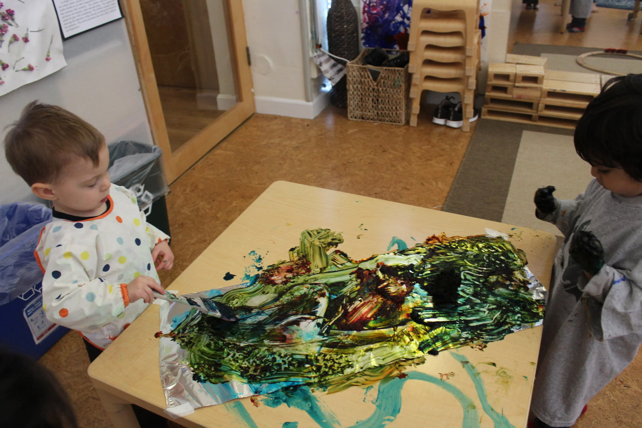    They are painting with Aluminum Foil paper using paintbrushes, sponge-like brush, sponges, and their hands.&nbsp; Foil painting is also a sensory activity.&nbsp; Rohan preferred to use his hands to explore the paint.&nbsp; He seems to enjoy the te