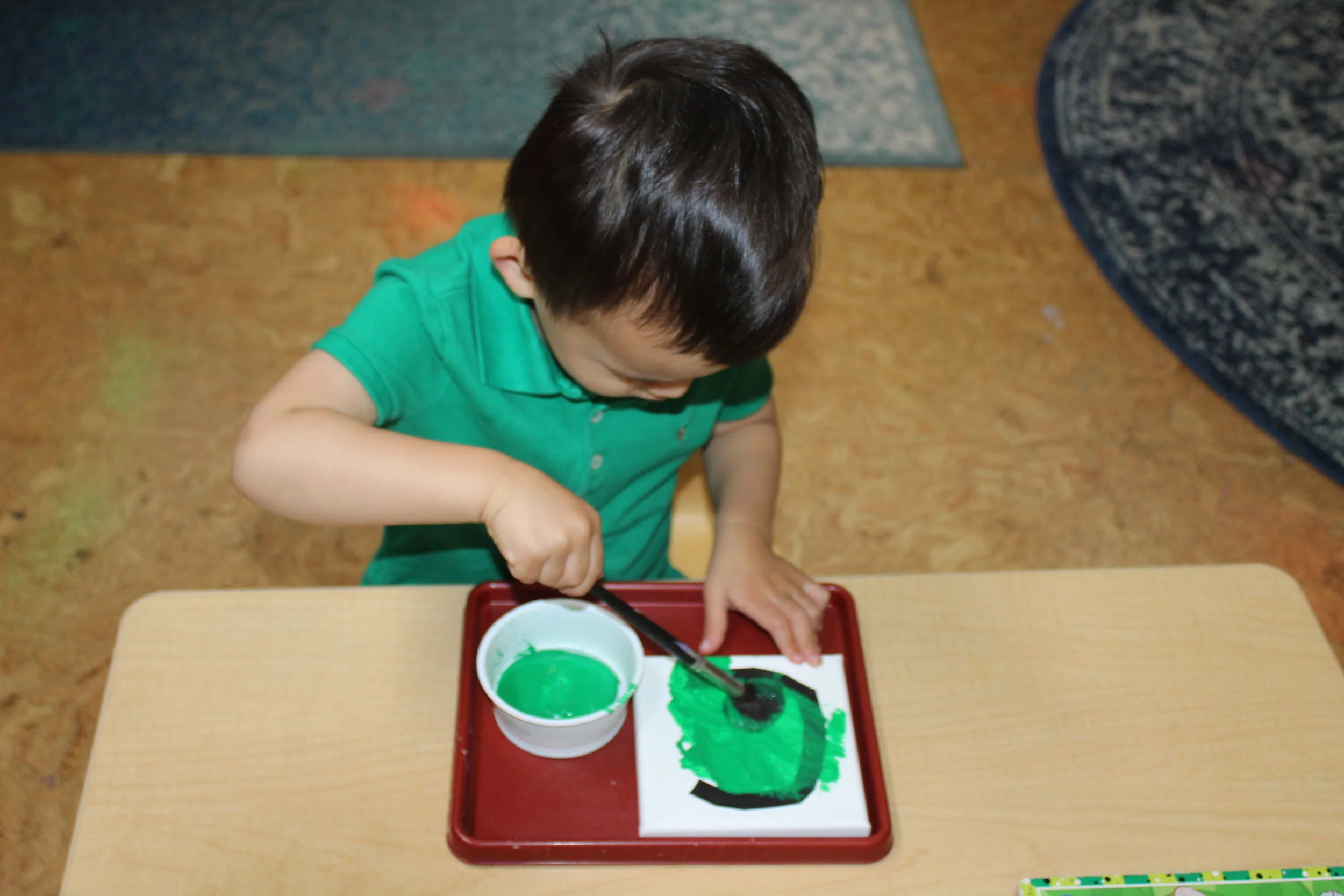 We used tape and a square canvas to create each child's first letter of their name. The children selected the color of their choice to paint over their letter, and then the tape was removed. Each canvas is displayed next to their picture. 