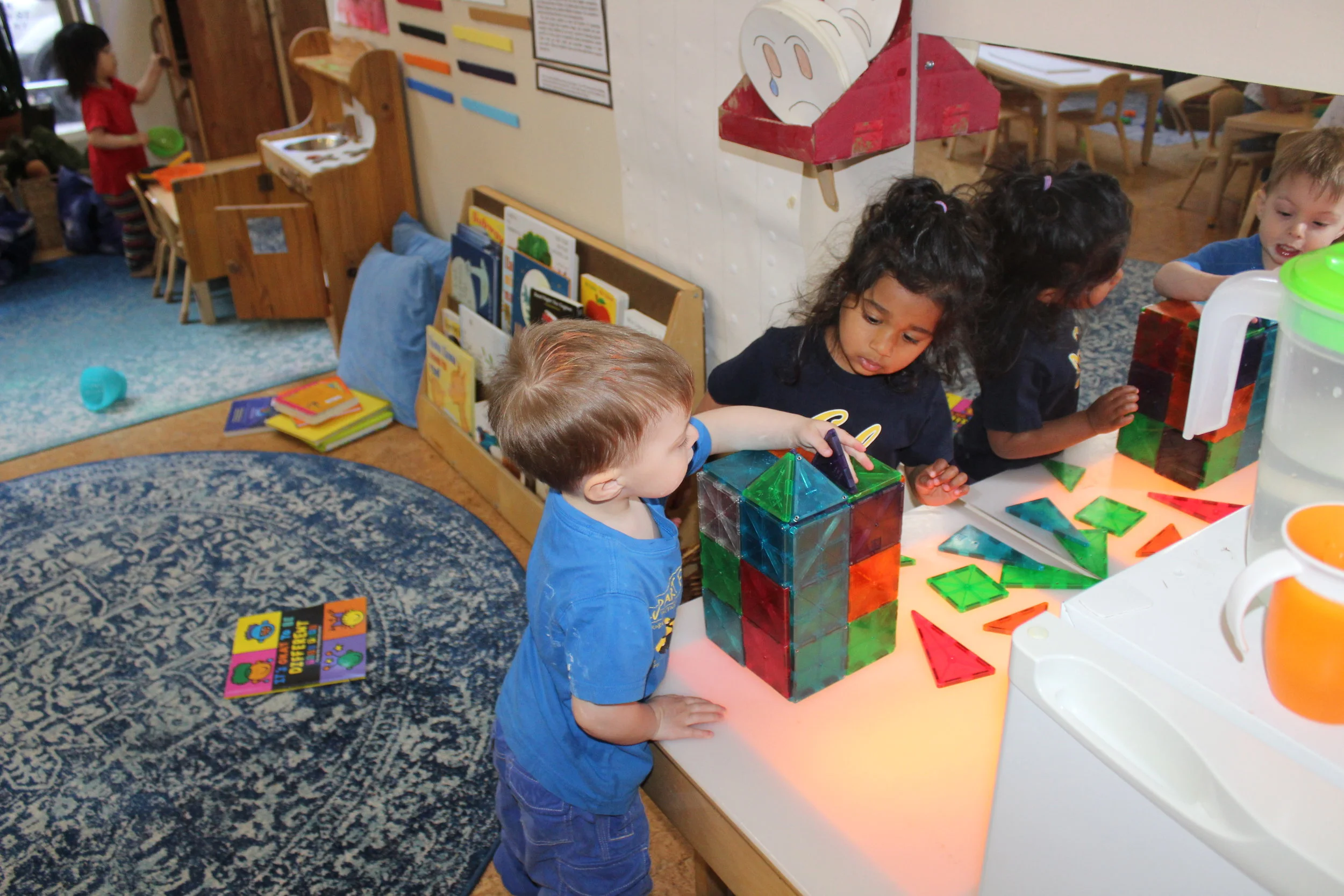  The children are collaboratively connecting and building a box using Magna-Tiles. 