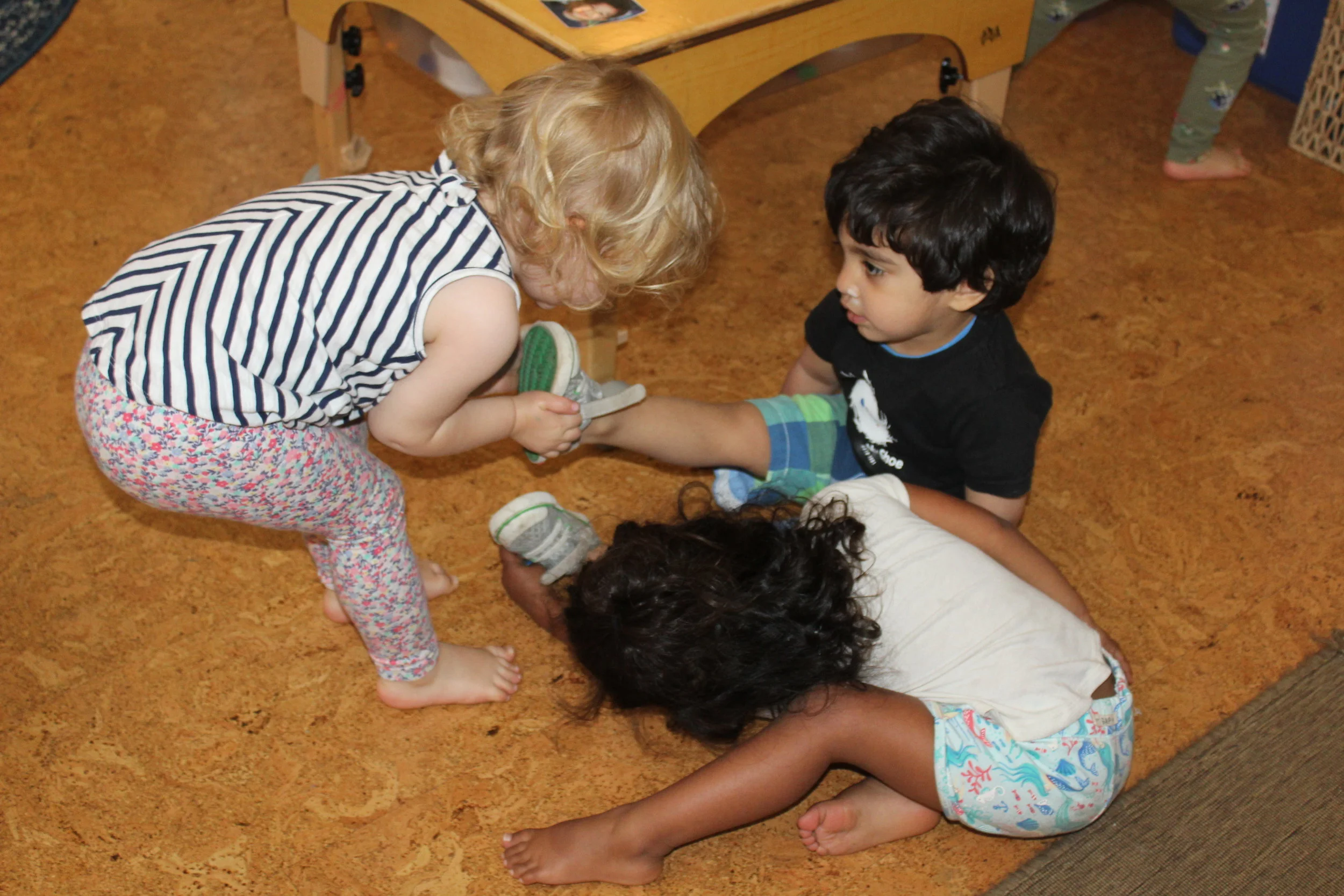  Rohan needed help with his shoes; therefore, Alexandra and Leela took the initiative to help him. They pulled, pushed, and pulled again.   