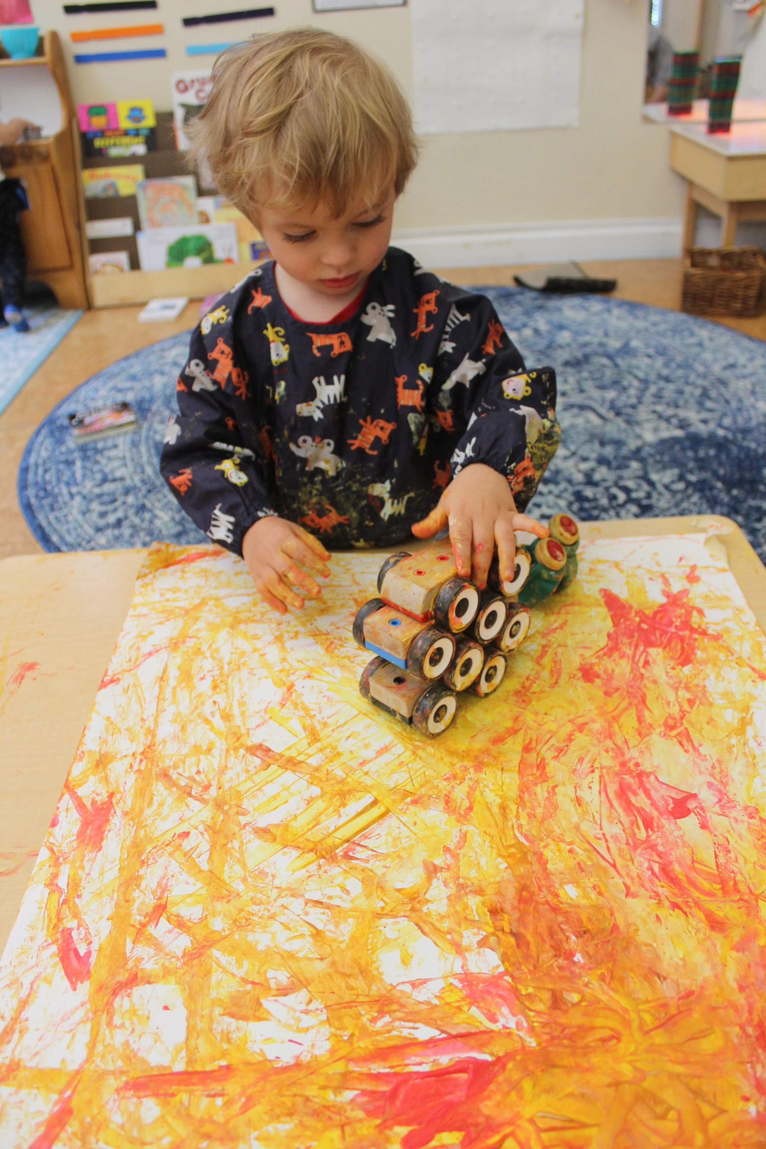 As the children engaged, they used their arm muscles to drive cars through the paint. They pushed the cars through one color and then rolled them on the paper. The children discovered that if they drove the cars in the opposite direction, the paint 