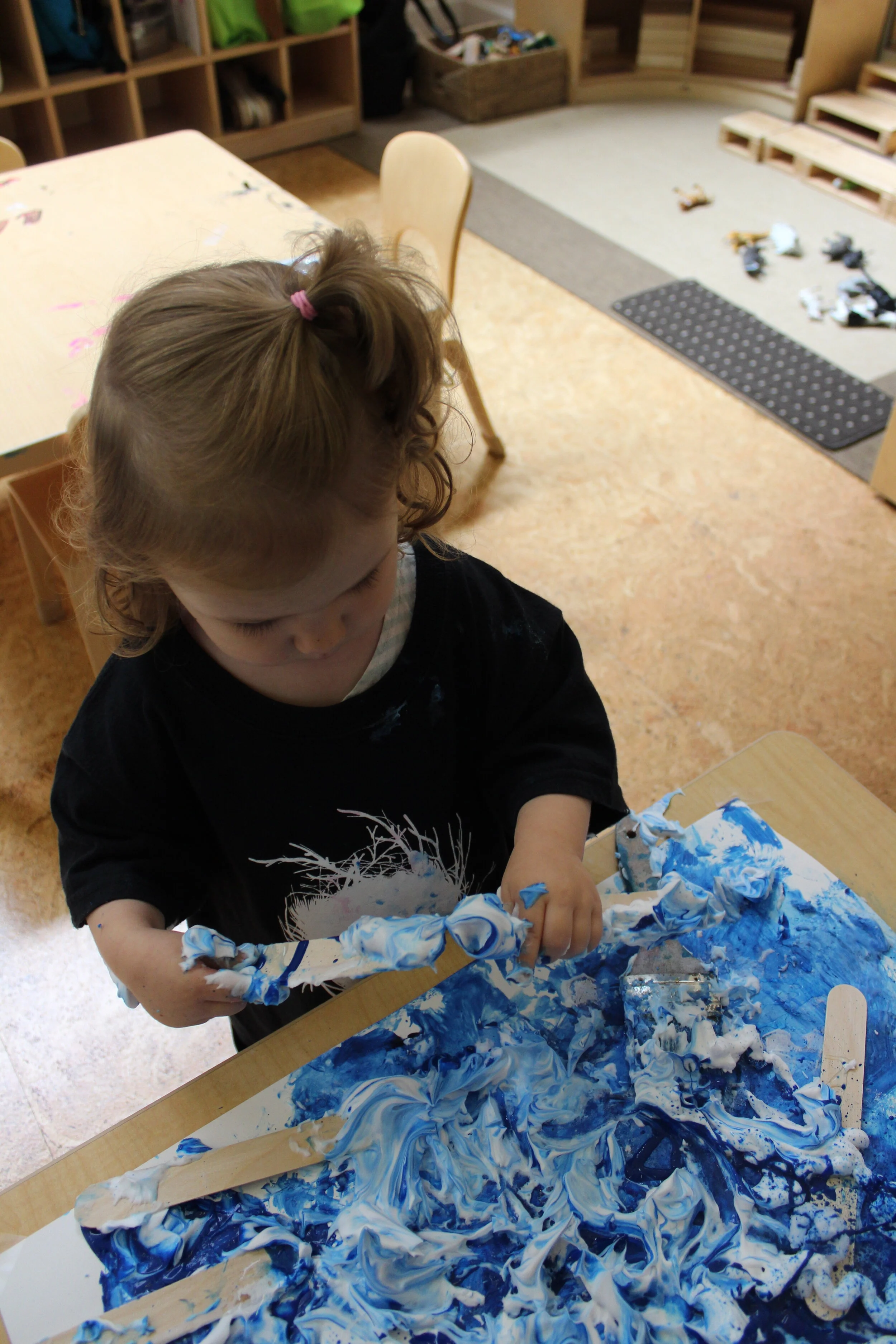  Ophelia appeared intrigued by the Popsicle Sticks, as she dipped them in the shaving cream and mixed the blue paint. All the children had a different technique in investigating and discovering new ways to explore. 