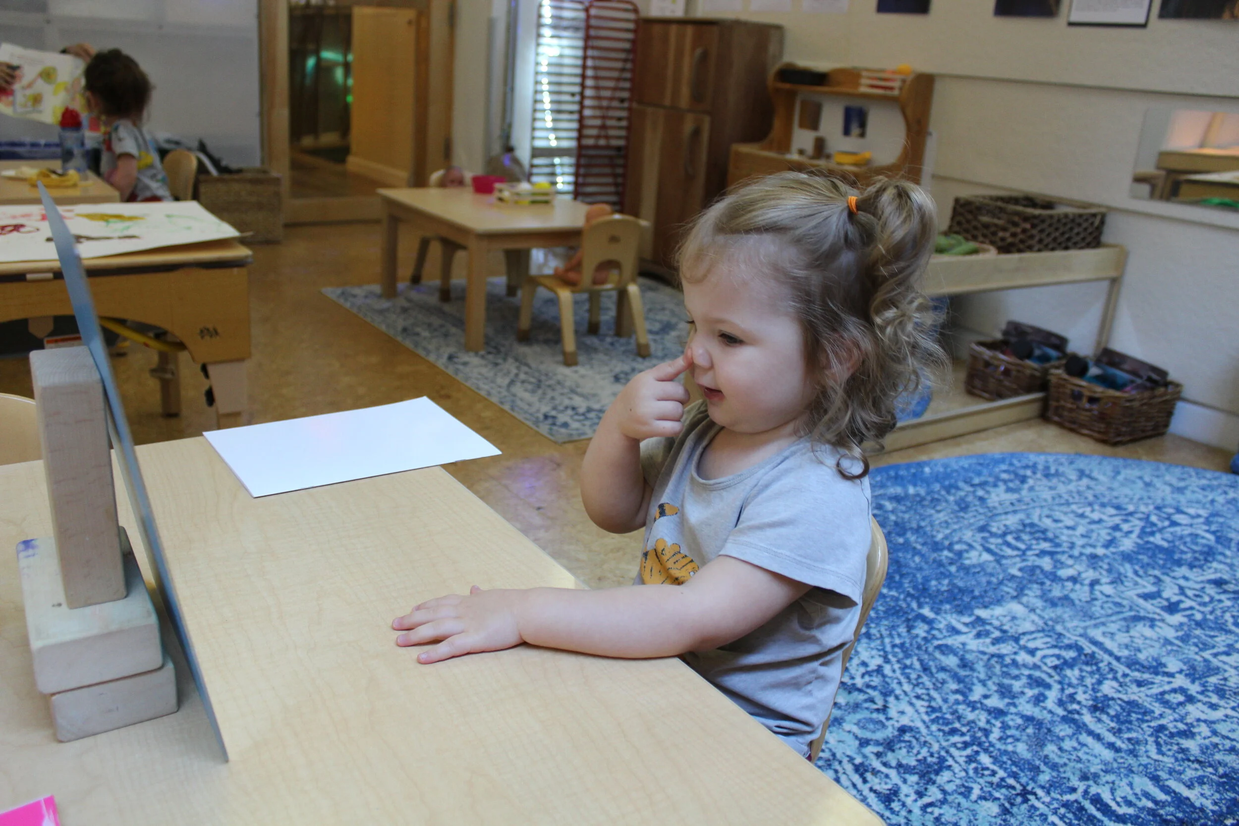  Self-portraits are drawn once a month. We sit one-on-one with a mirror, paper, and a sharpie marker. The mirrors encourage children to look closely at the shapes of their facial features. They observe and explore their image. As they look at their f