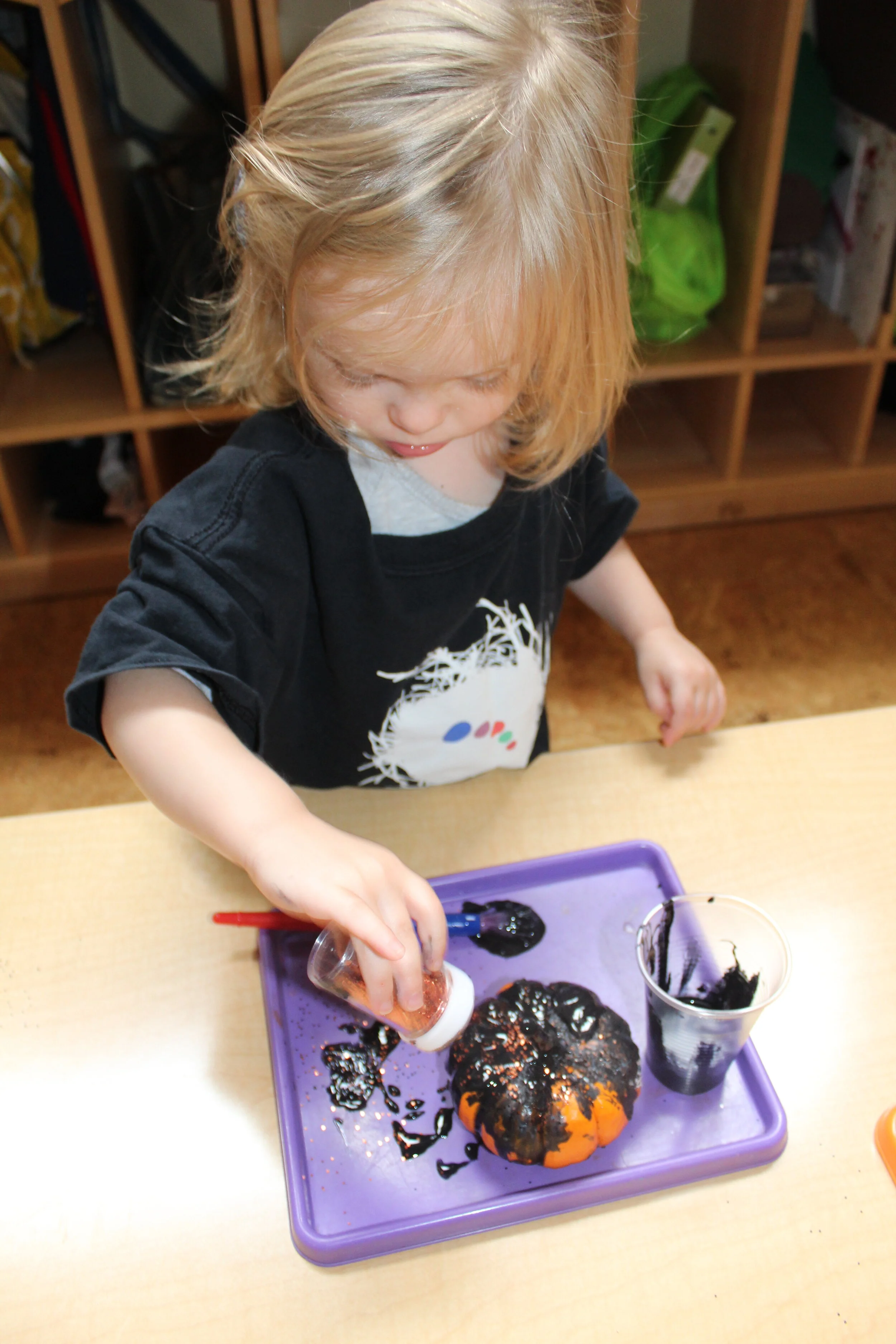  Three different colors were provided as choices to paint the small pumpkins orange, white, and black. Orange and black glitter was also available for the children to sprinkle on the pumpkins. They painted from the top to the bottom of the pumpkins o