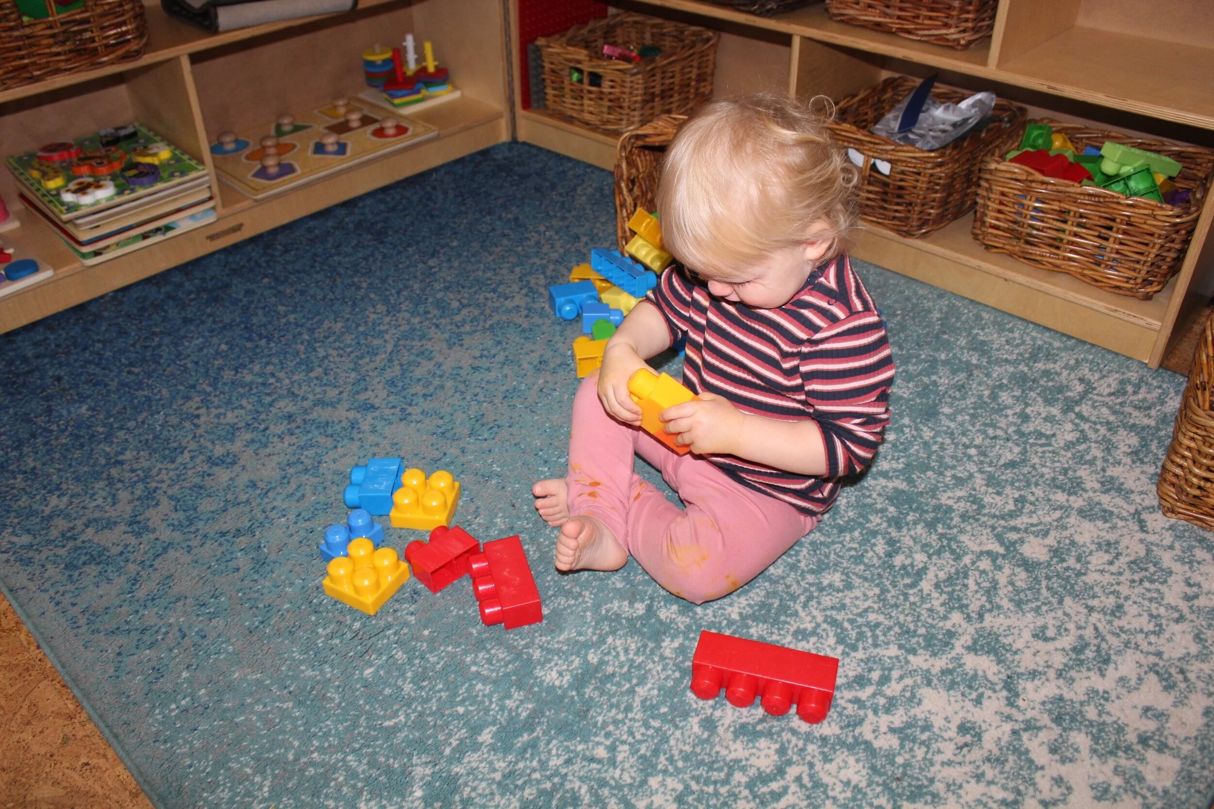  Blake appeared interested as she connected a yellow and orange Lego block. She joined and then pulled them apart. Her facial expression was full of wonder as she noticed how she could interlock both Legos and then pulled apart. Providing time and op