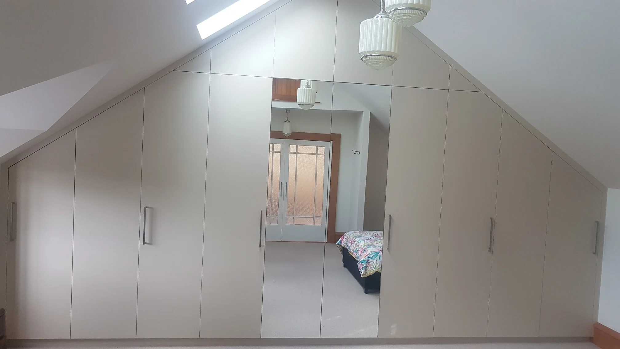 Large custom wardrobe in room with A-frame roof