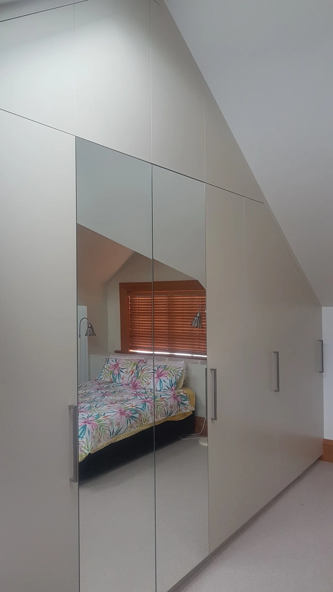 Large custom wardrobe in bedroom with sloped roof