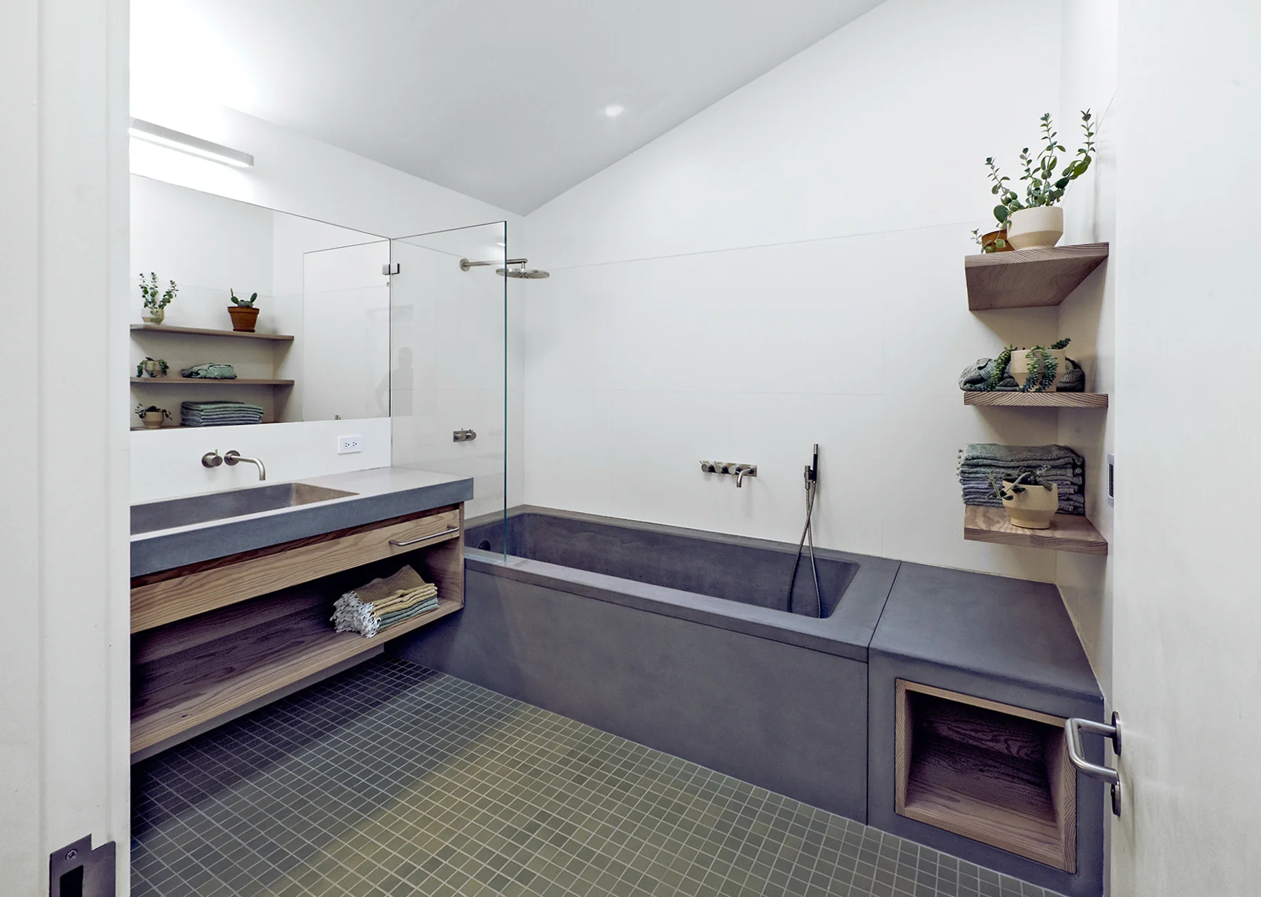 The bathroom is a light-filled cozy environment, with radiant heated Heath tile floor. The custom vanity and tub are made of concrete with Douglas fir accents. The fixtures are from Denmark’s Vola, with a brushed stainless steel finish. Photography by Robert Cardin