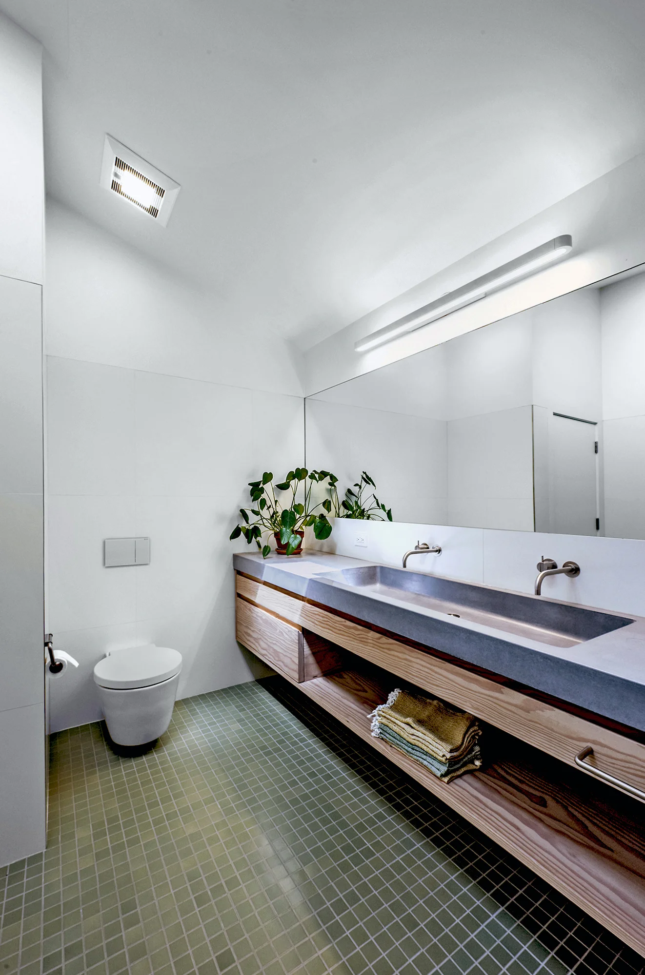 The toilet is a wall-hung to maximize space, Duravit Stark 1, with Geberit in-wall tank carrier. The concrete vanity has an integral trough sink and Vola drain. Photography by Robert Cardin