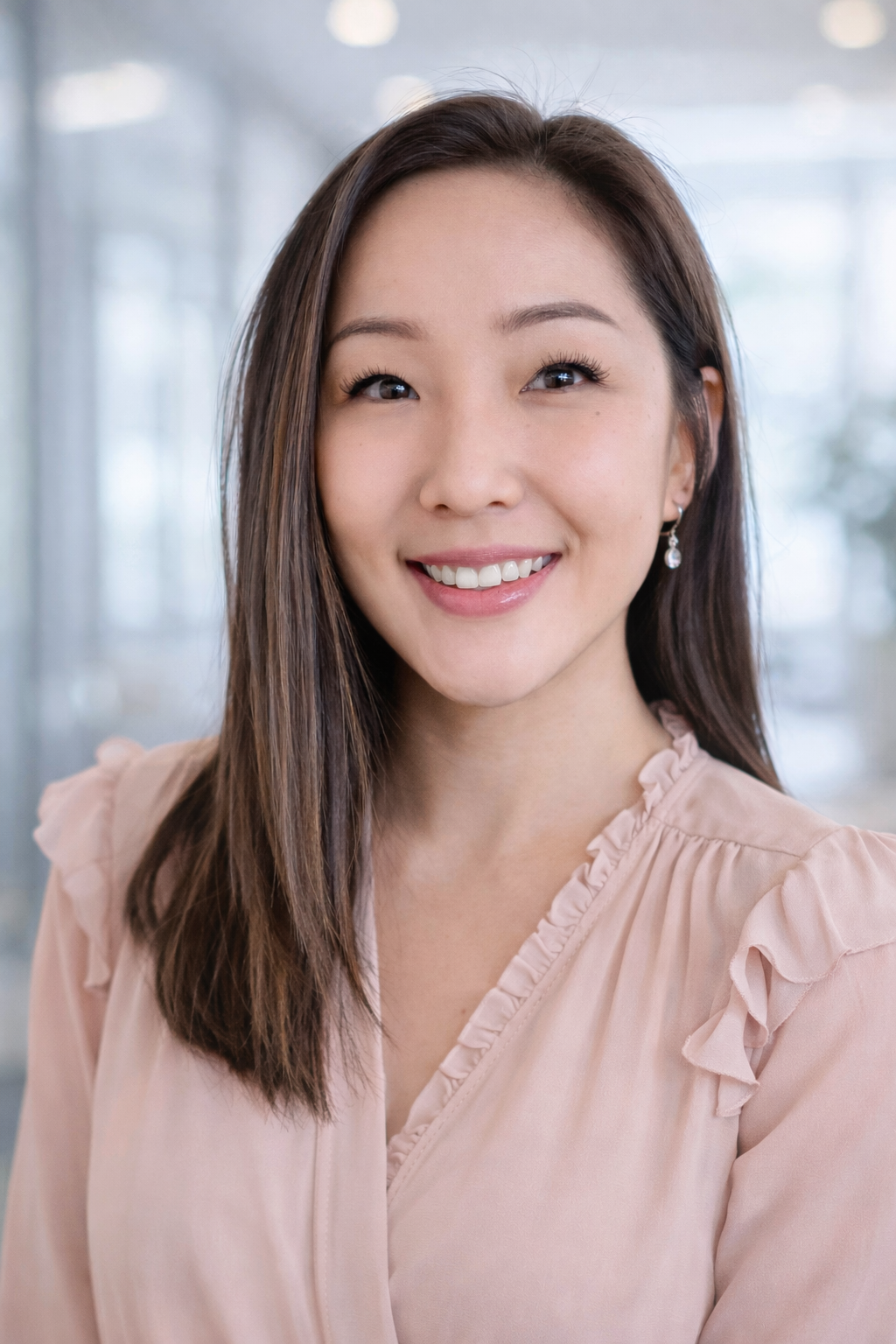 A woman with dark hair wearing a leopard print headband and a light-colored top outside on a sunny day, smiling at the camera.