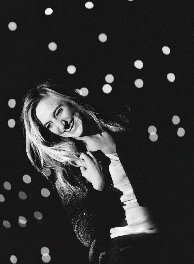 High school senior laughing in front of Christmas lights