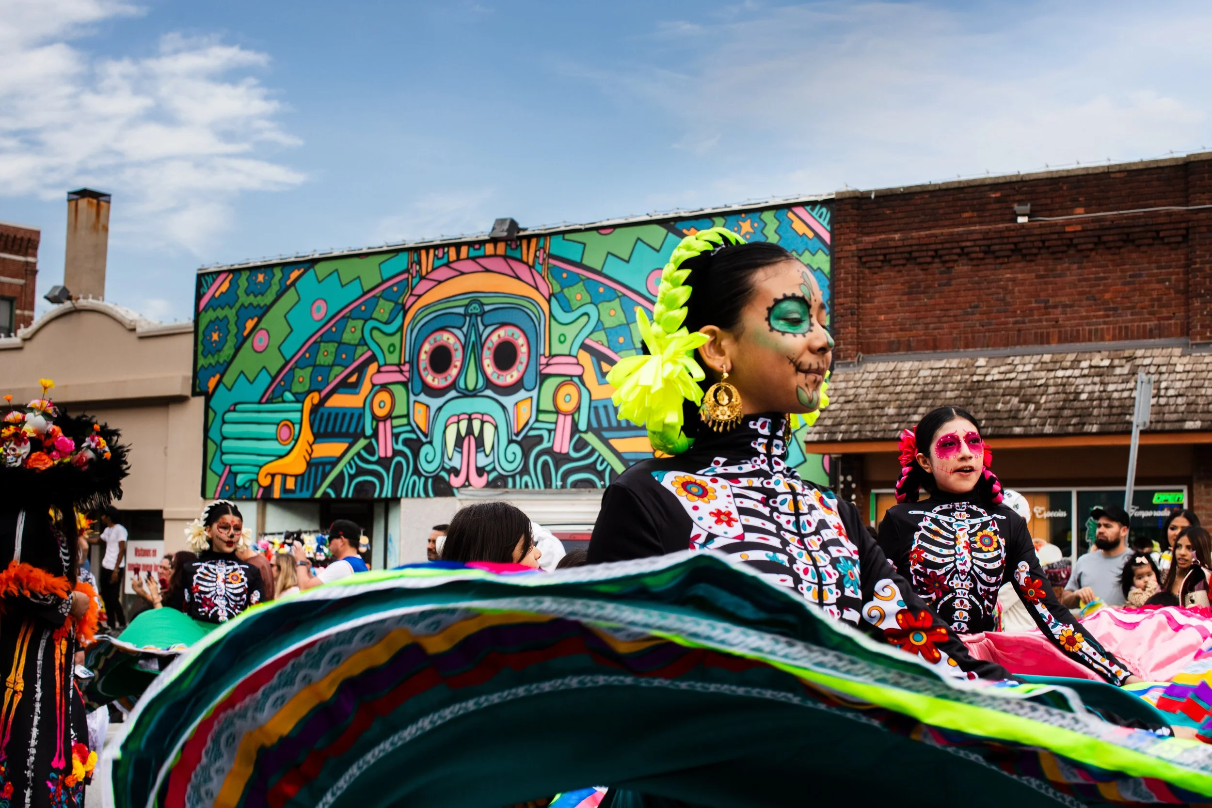  Girls in Jalisco Ribbon dresses in La Catrina design walking in the dia de los muertos parade in Omaha. 
