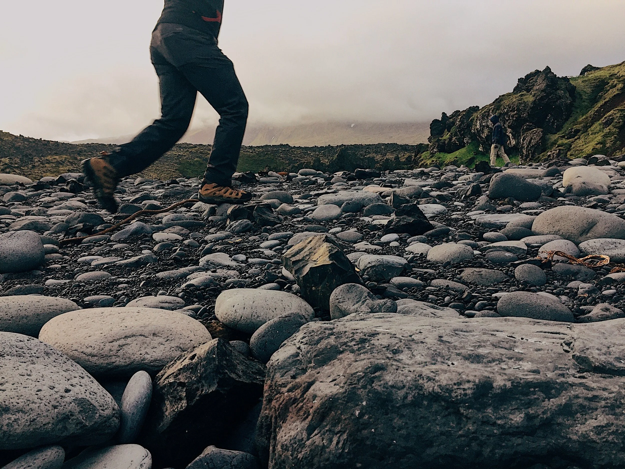 Beach at Dritvik filled with polished dark stones from the beating ocean waves nearby.
