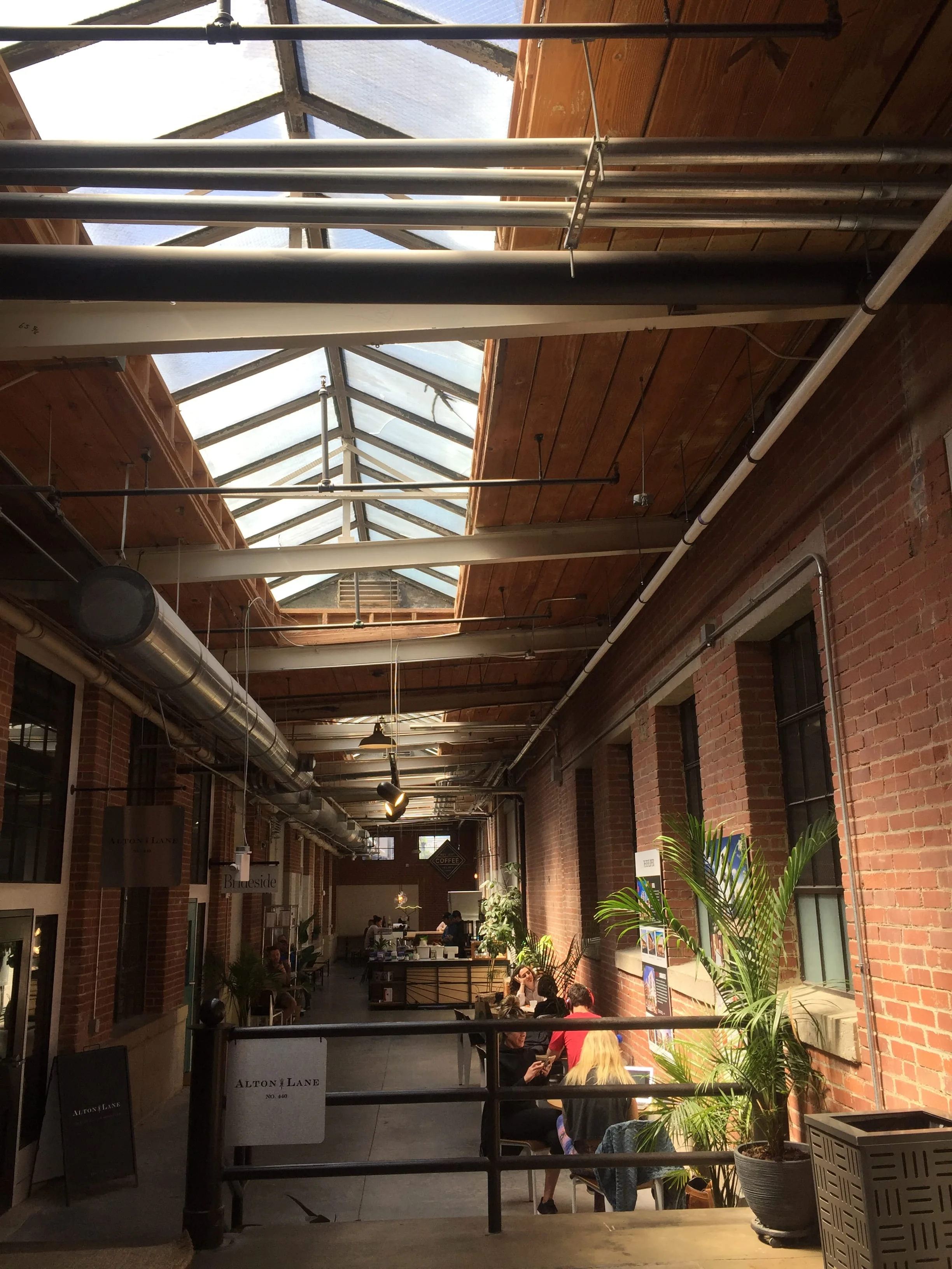 Charlotte Not Just Coffee space with sky lights and brick wall. Airy space to work in. 