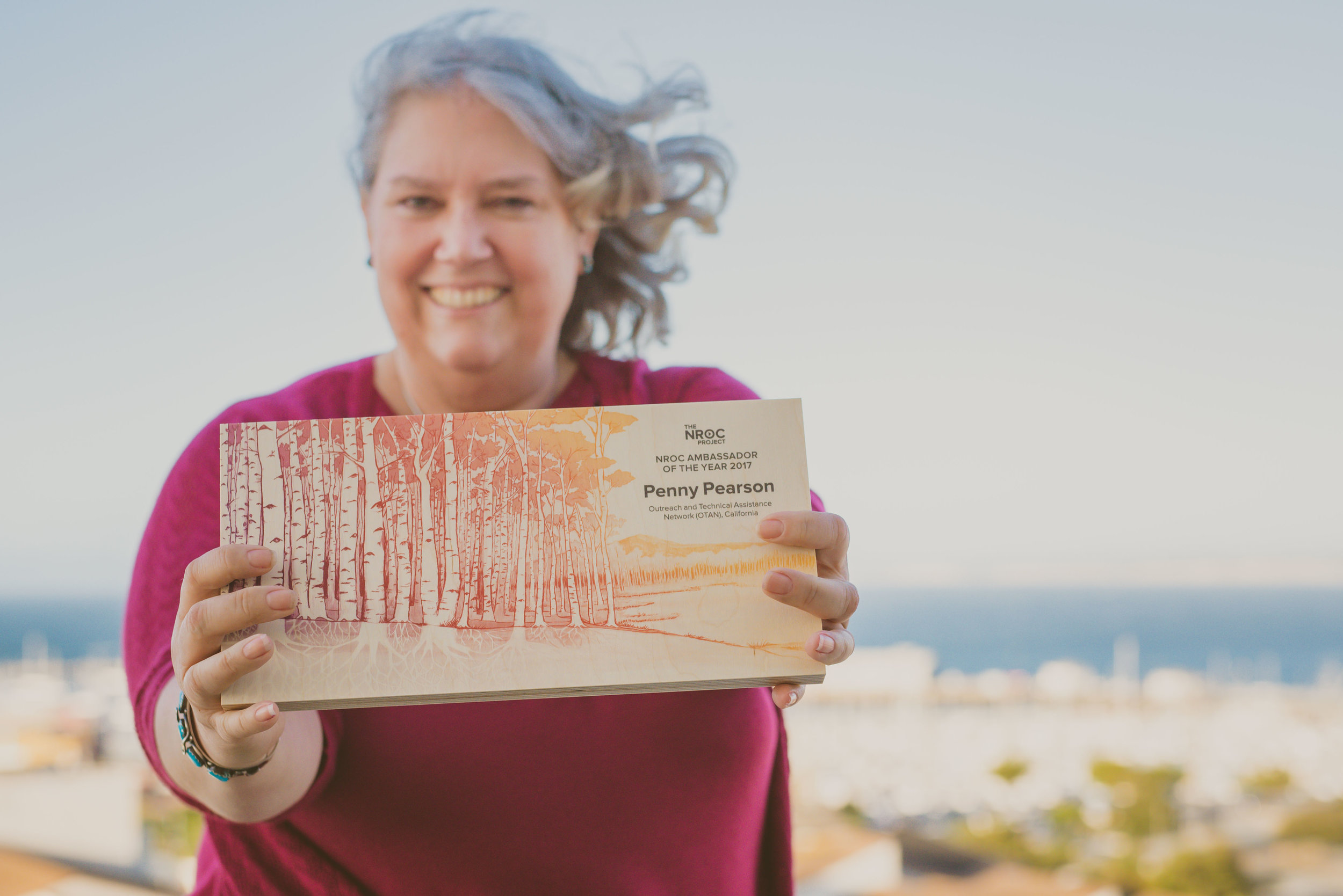 2017 Ambassador award winner and California Adult Education professional, Penny Pearson proudly displays her award featuring the Networked for Change aspen illustration.