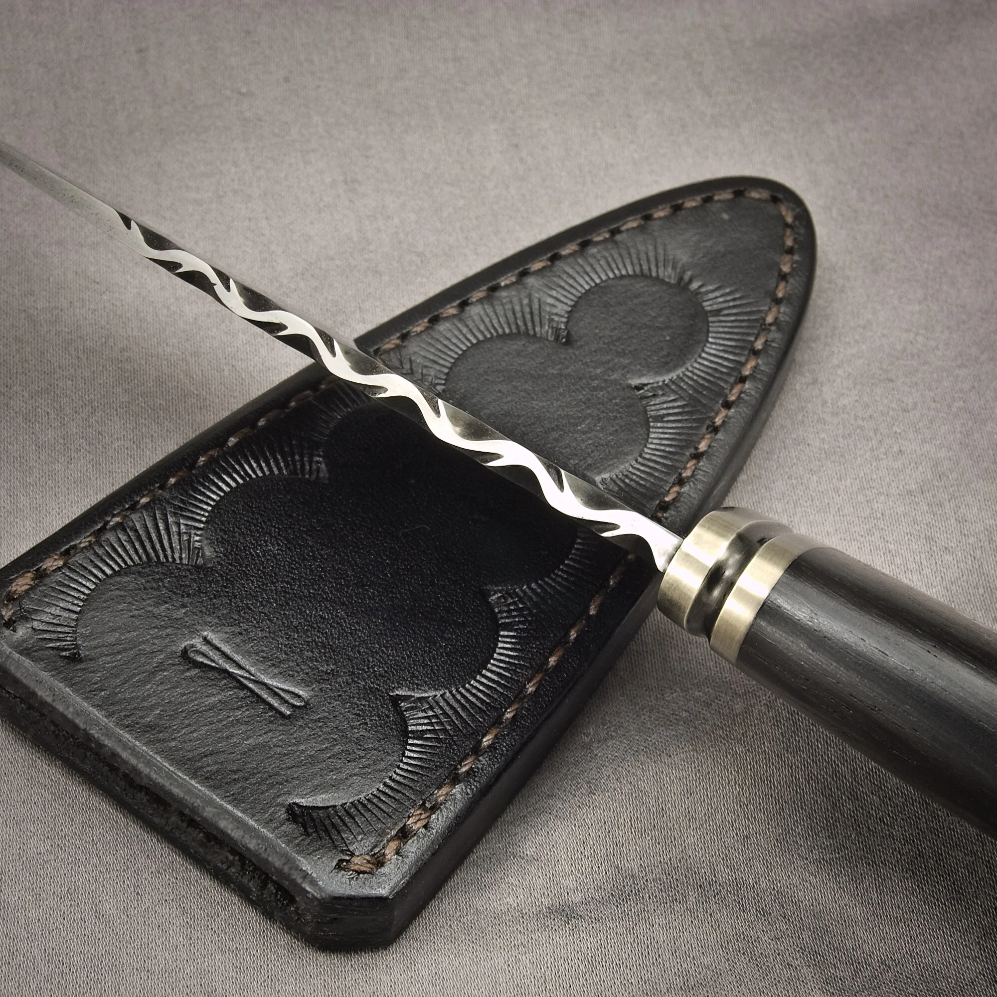 Detail of filework on spine and tooled leather sheath.