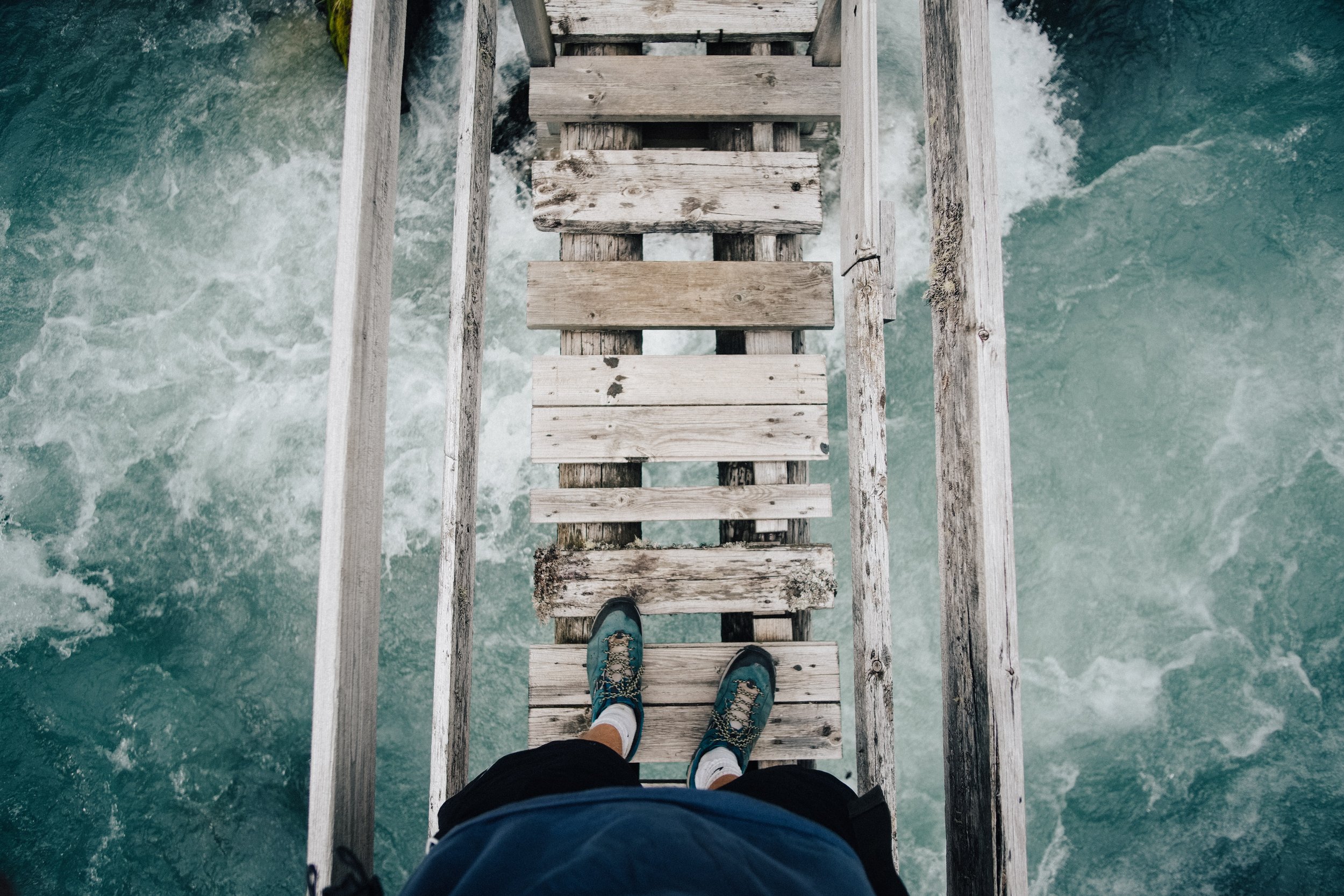 Person walking on a bridge over rapids representing exposure therapy for anxiety