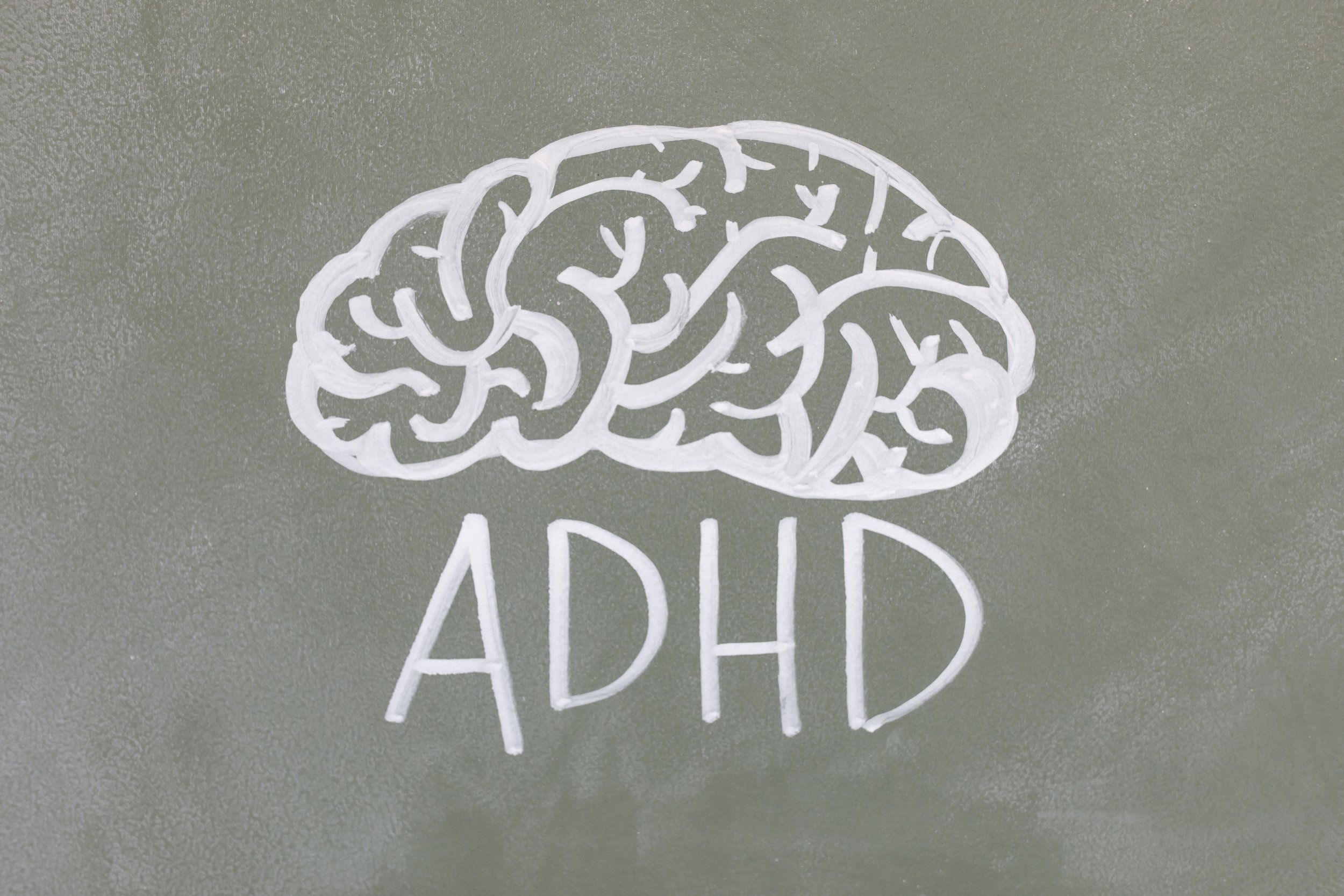 A brain on a chalkboard with “ADHD” written under it, representing treating ADHD.