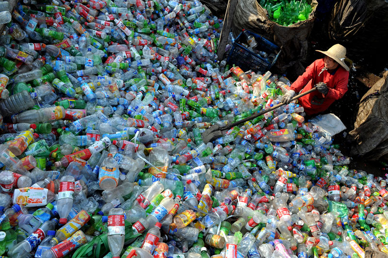A Chinese worker piles up the plastic bottles collected at a recycling center in Hefei. Courtesy: Asia Society