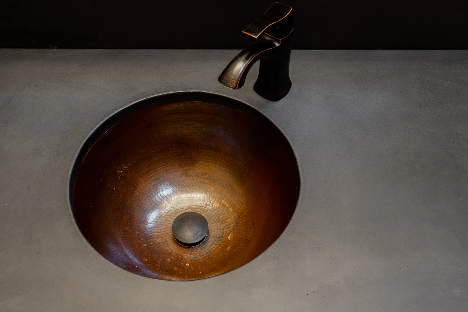 Onyx black concrete vanity with hammered Bronze under mount sink