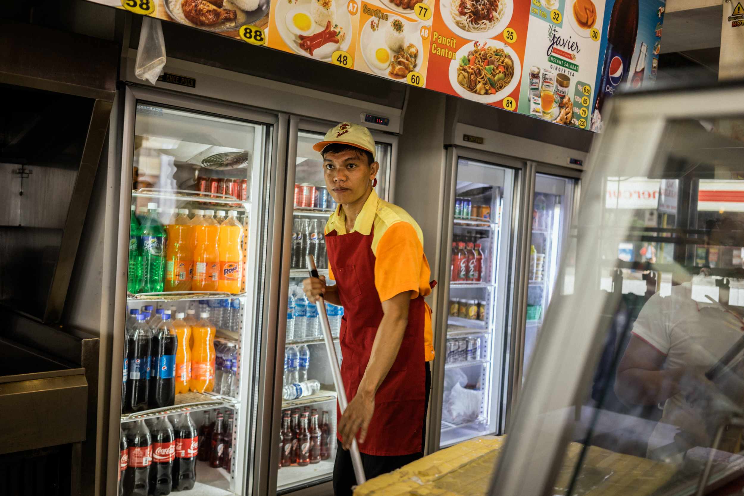 Kalibo, Philippines - September 20, 2015: Emmanuel Concepcion mops in the local fast food chain where he is currently employed after being repatriated from a fishing vessel. Emmanuel is a victim of a Singapore-based maritime manning agency that collected illegal placement fees from him, stationed him on a Taiwanese fishing vessel where he faced inhumane circumstances, and then failed to give him the salary he was promised. Hannah Reyes