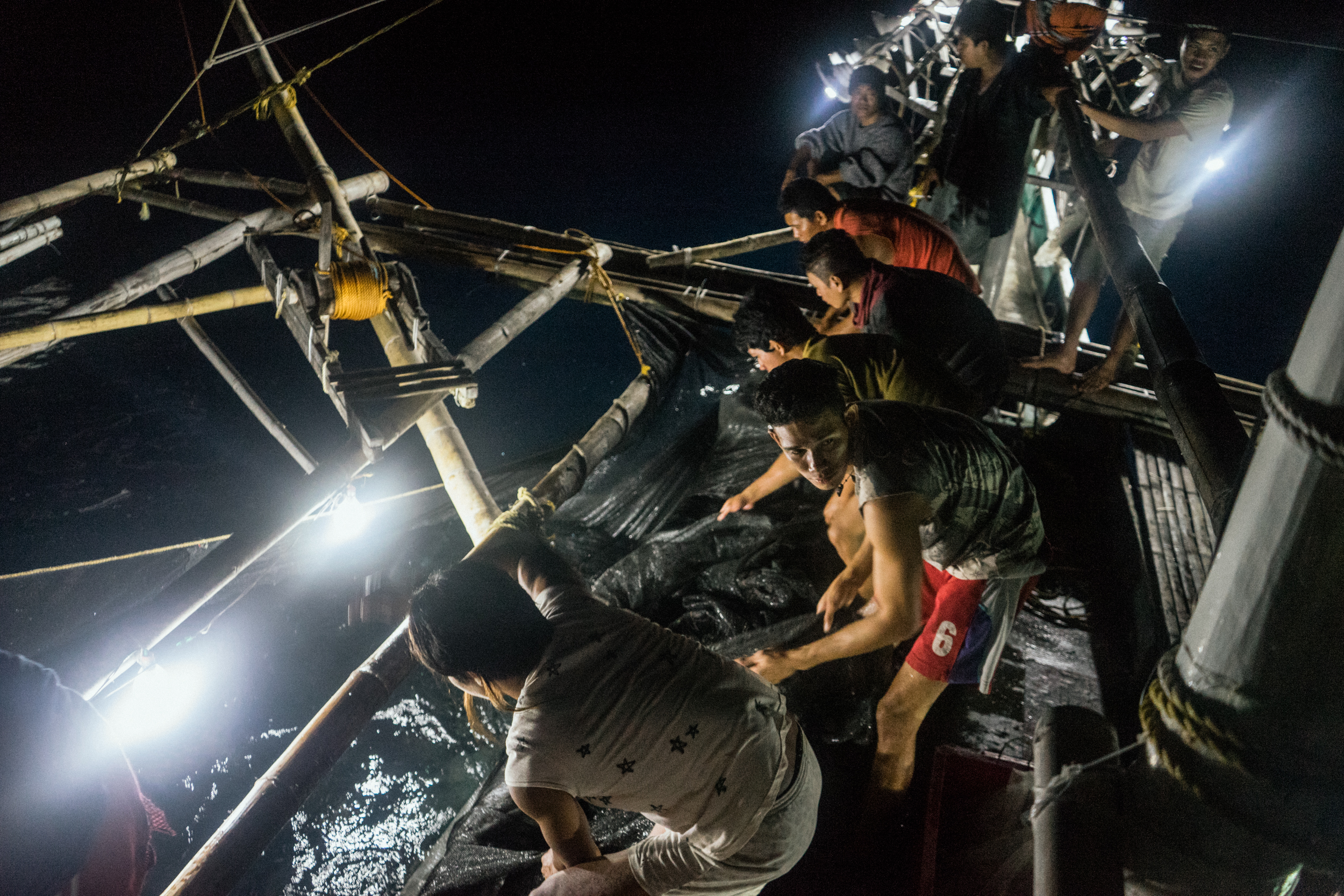  Kalibo, Philippines - September 21, 2015: Fishermen work in a local fishing boat. Members of the crew, who make approximately 35 USD per month, have expressed their desire to work on a larger fishing vessel for the promise of a higher income despite