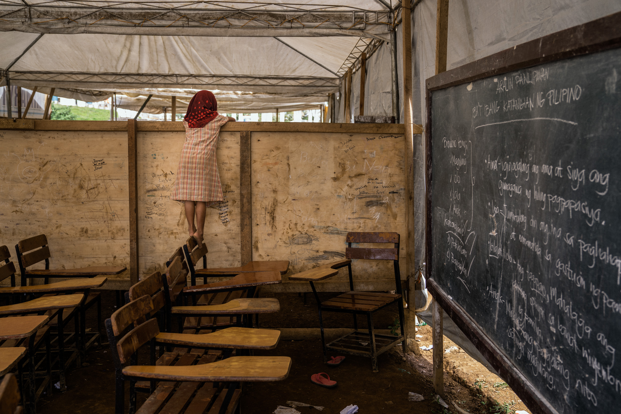  A child is seen in a makeshift classroom in an evacuation camp.  