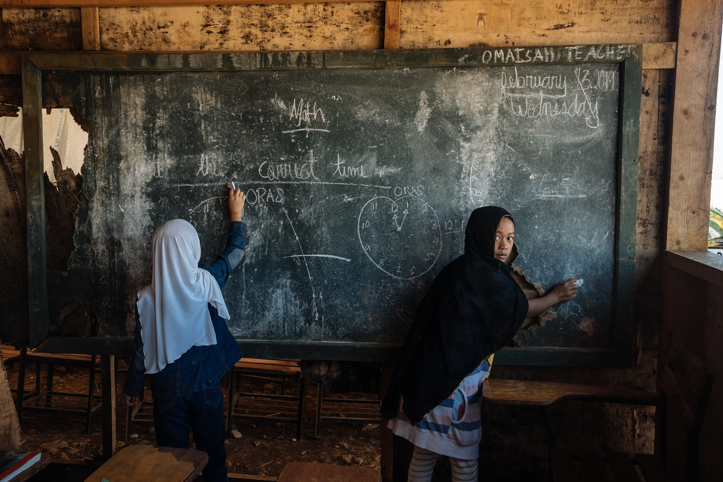  Young girls are seen erasing the blackboard of their makeshift classroom in a camp for internally displaced youth in Marawi City.  
