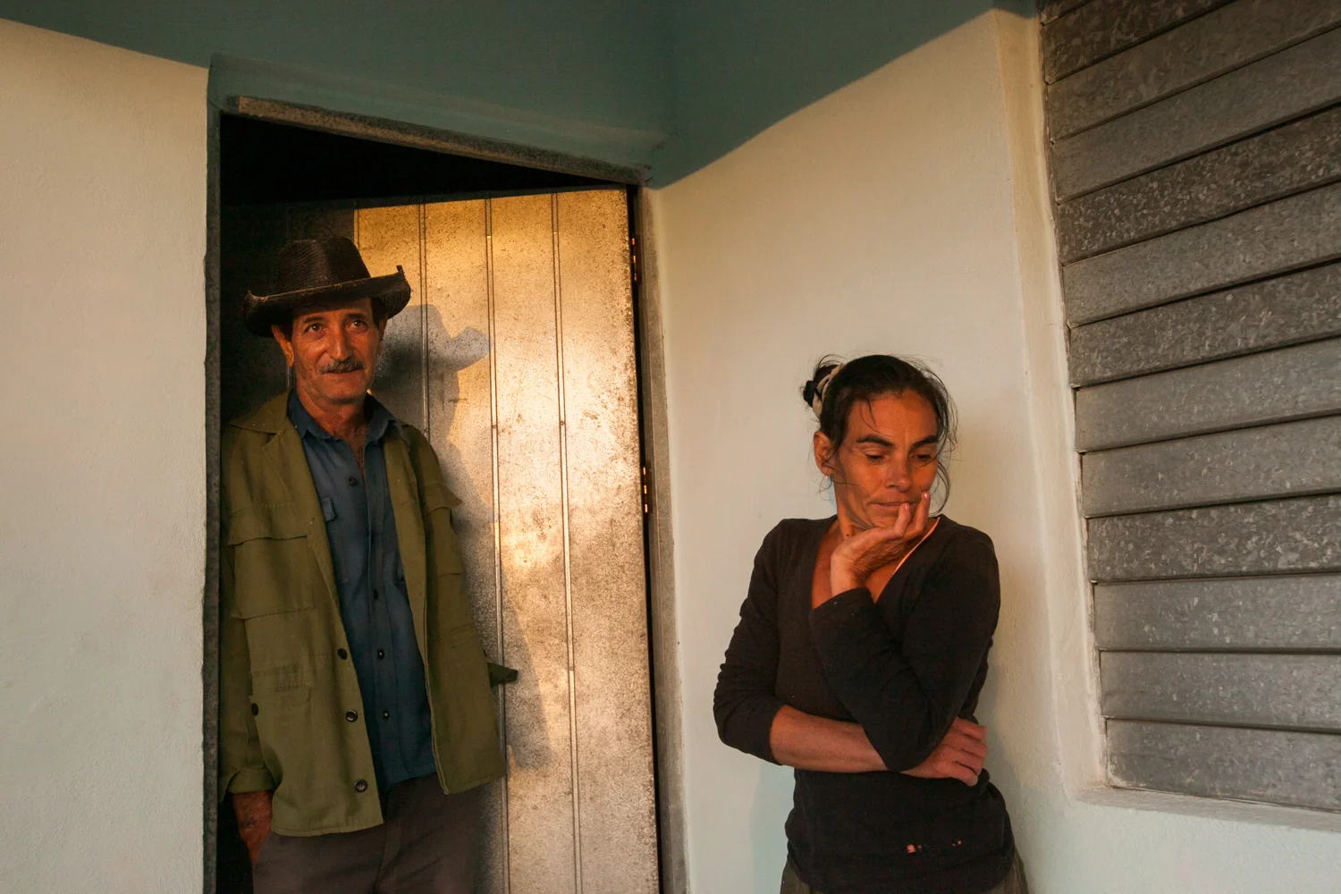 In Cienfuegos, Cuba, a woman and man stand in the doorway of their home.