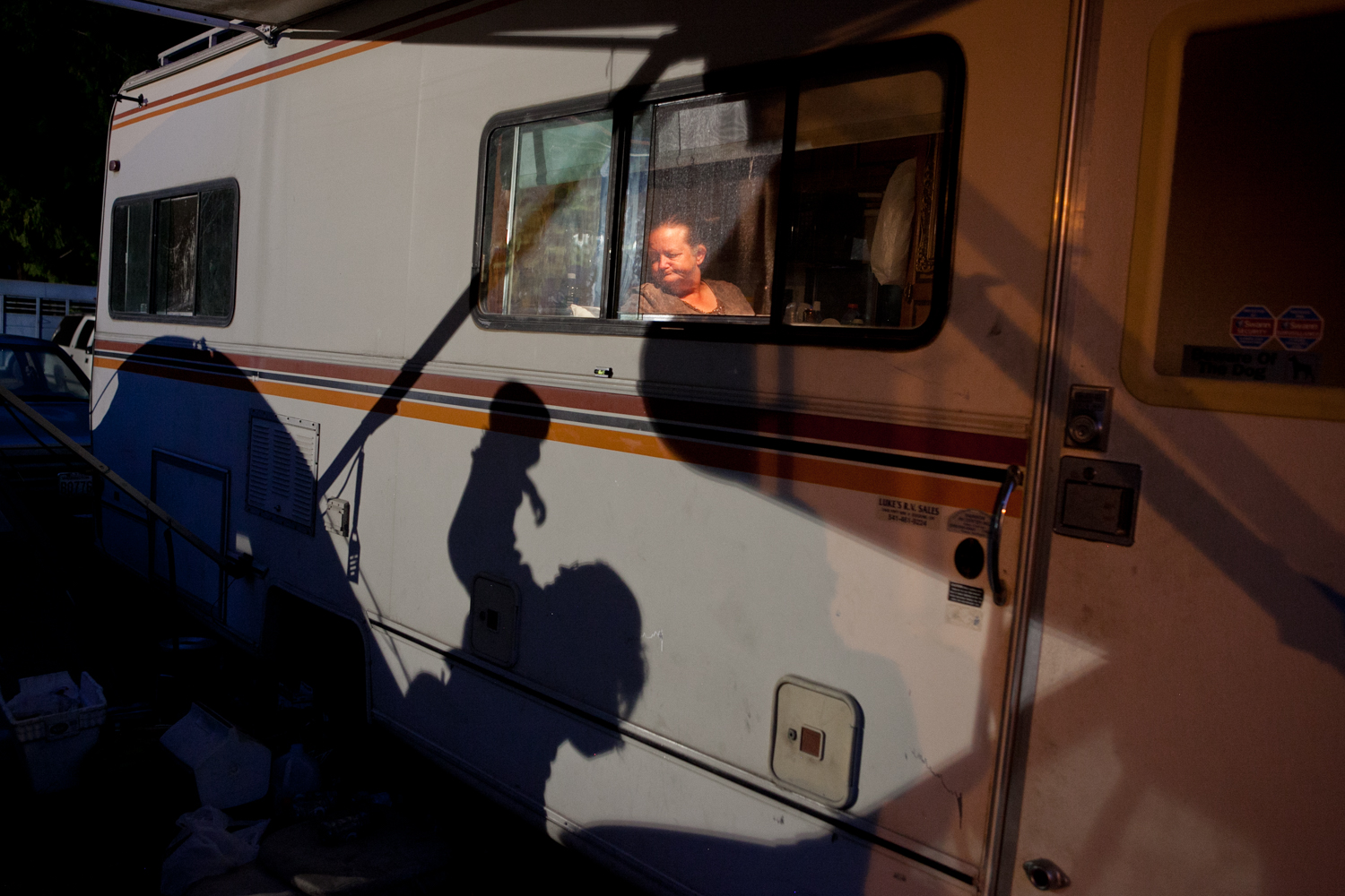 It is quite common that families travel together with the carnival. In camp, one woman observes her neighbors - a mother and daughter - through the window.